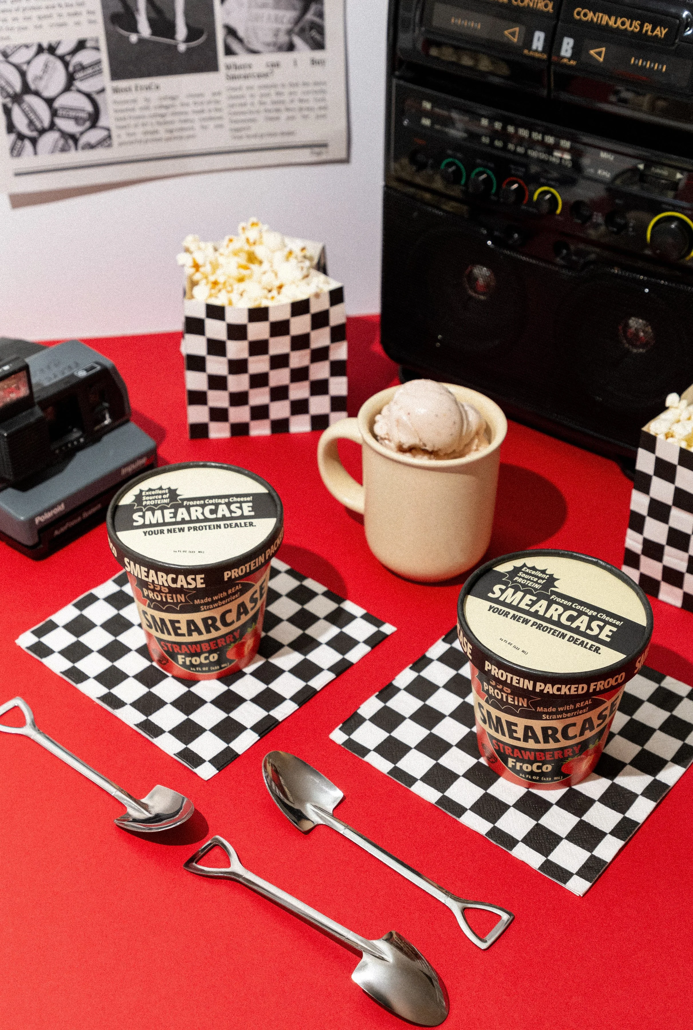 Smearcase Strawberry protein ice cream, a mug with ice cream, a vintage camera, and spoons. Commercial product photography for CPG, food, and beverage brands, creating e-commerce, social media, and marketing-ready product images.