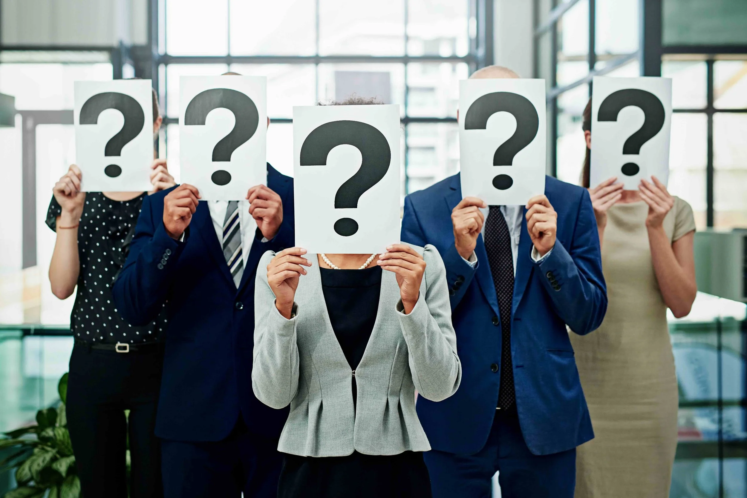 Confused business people with question mark cards hiding their faces
