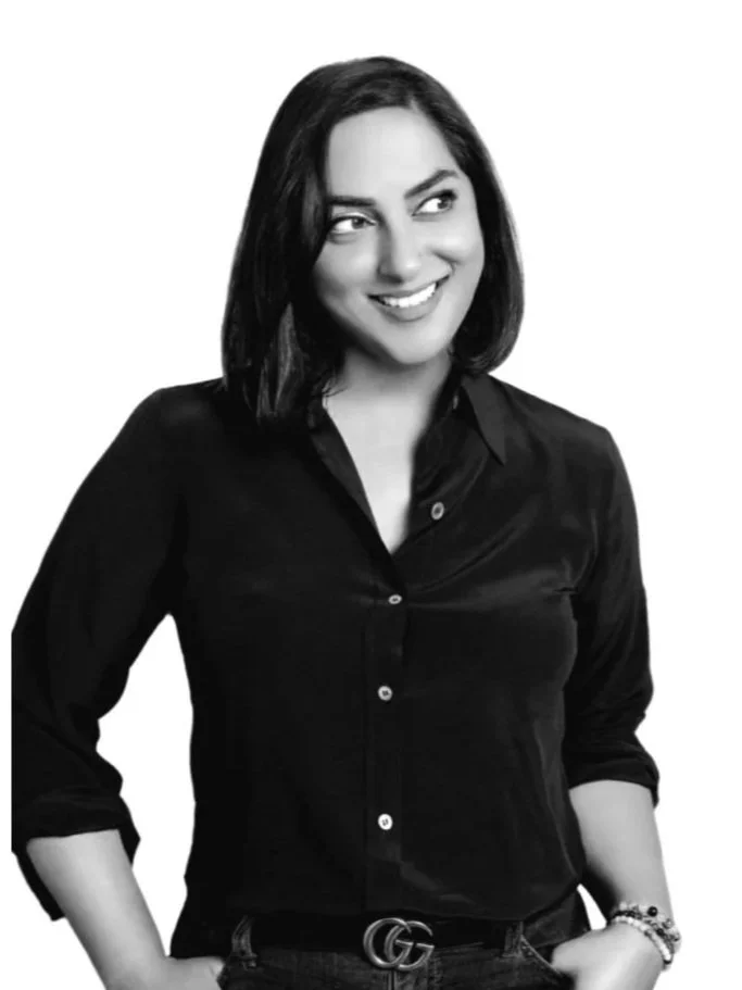 Black and white photo of a woman with dark hair wearing a black button-up shirt, smiling and looking to her right.