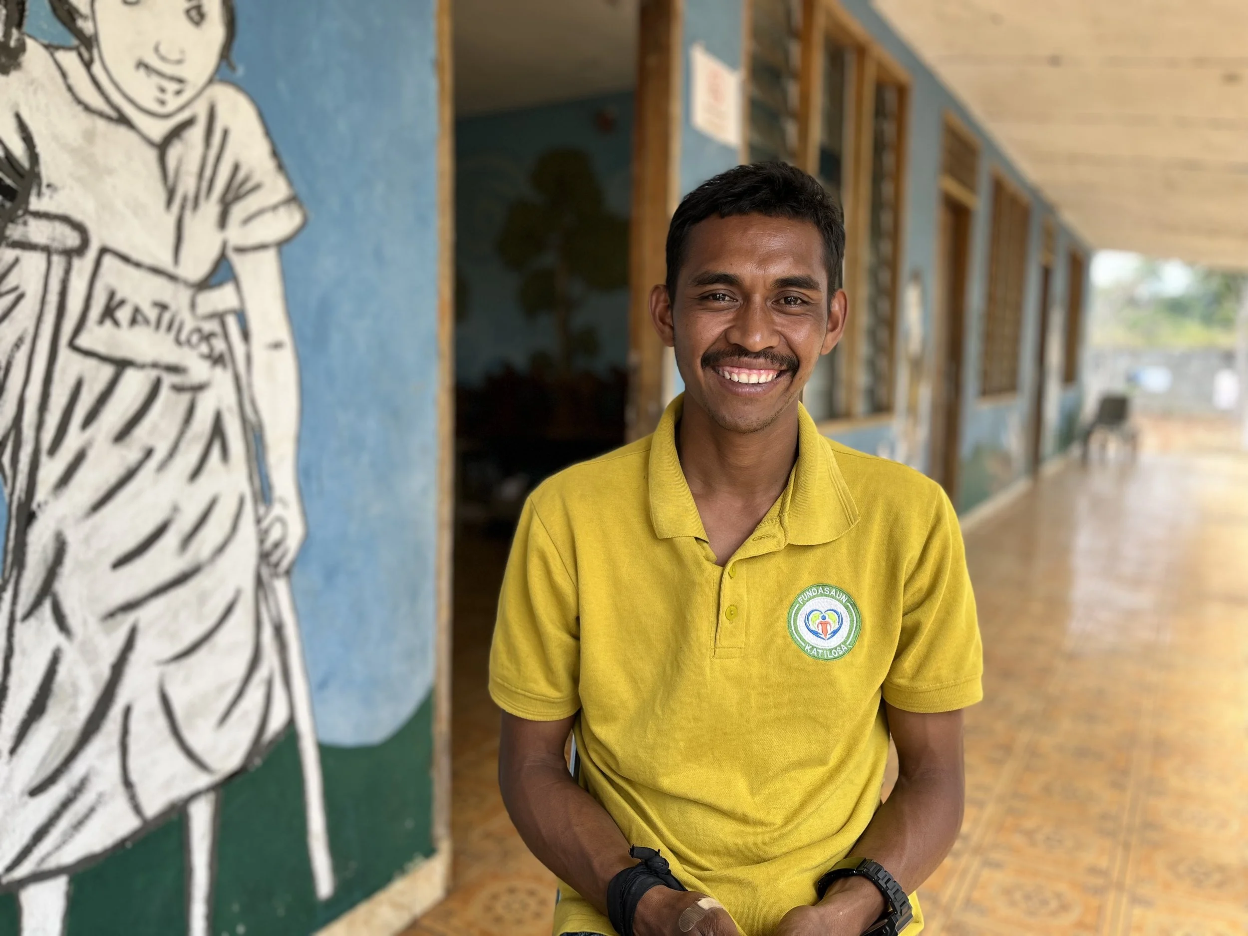 Teacher Agostino and former ICFP graduate at KATILOSA smiles for the camera during a candid sit-down interview about the realities of teaching students with a disability and the successes and challenges he has faced in his experience