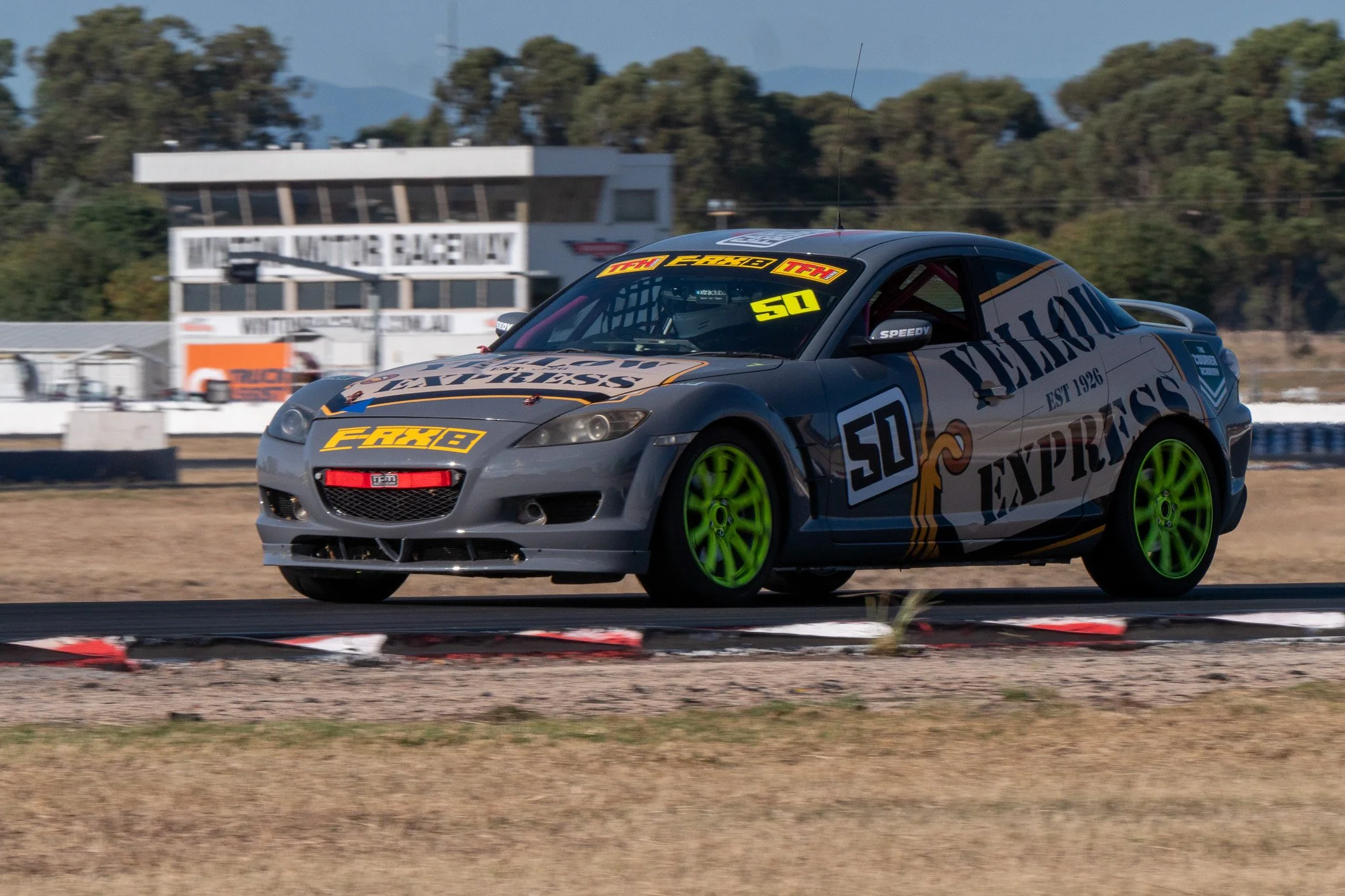 A race car on a track with green wheels and a Renault logo, decorated with branding for 'YELLOW EXPRESS' and the number 50, during a racing event.