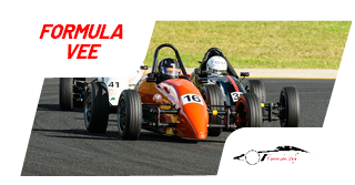 A Formula Vee race car on a racetrack with a green grassy area in the background.