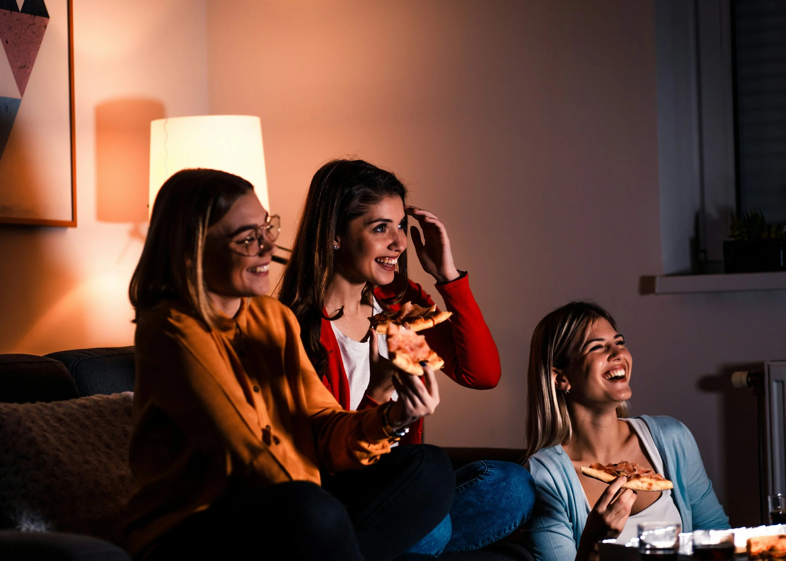 Woman watching television from a couch at home in the evening.
