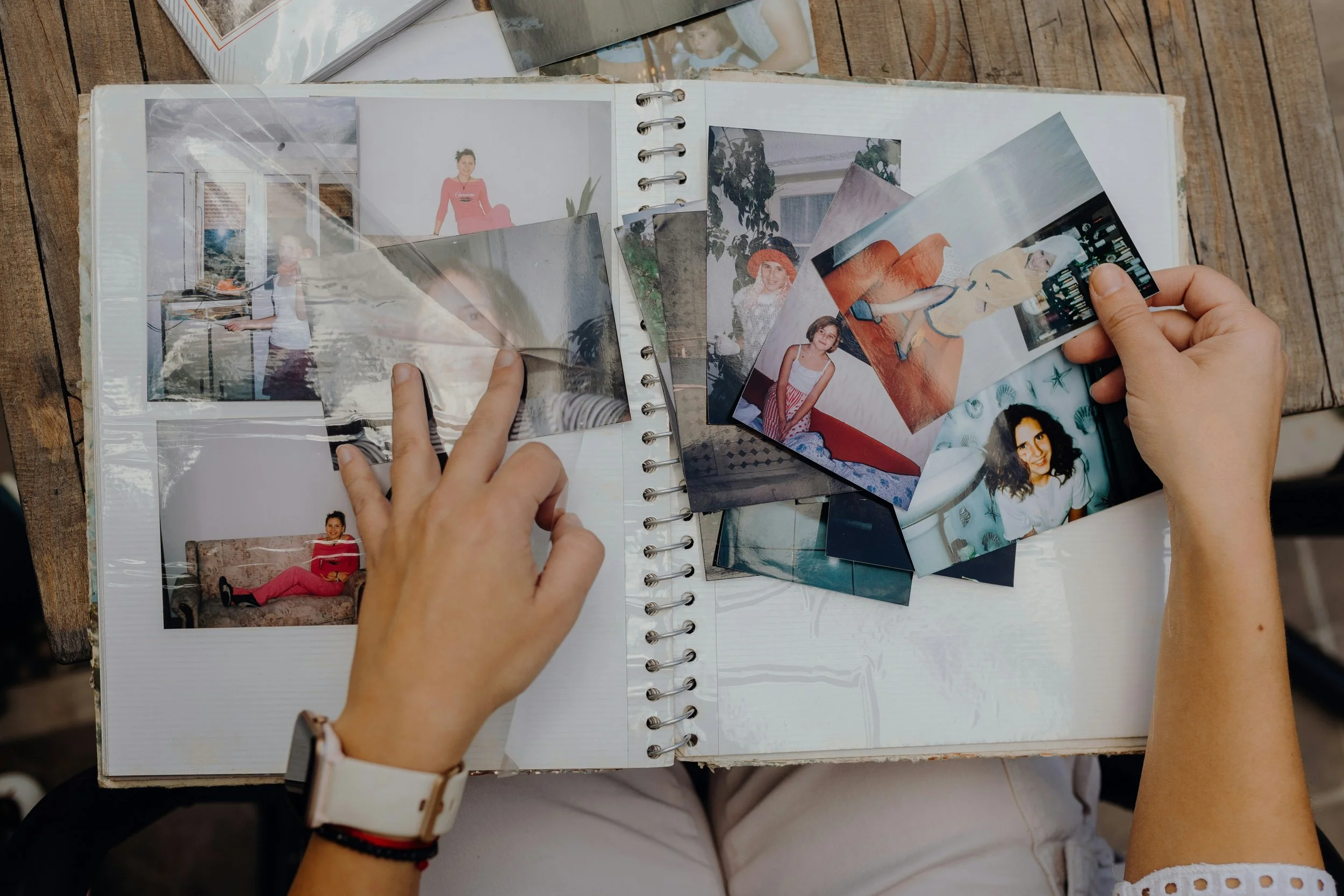 Adult looking through old family photographs while reflecting on childhood family roles, including the responsible child, peacemaker, and rebel, and their impact on adult relationships and mental health