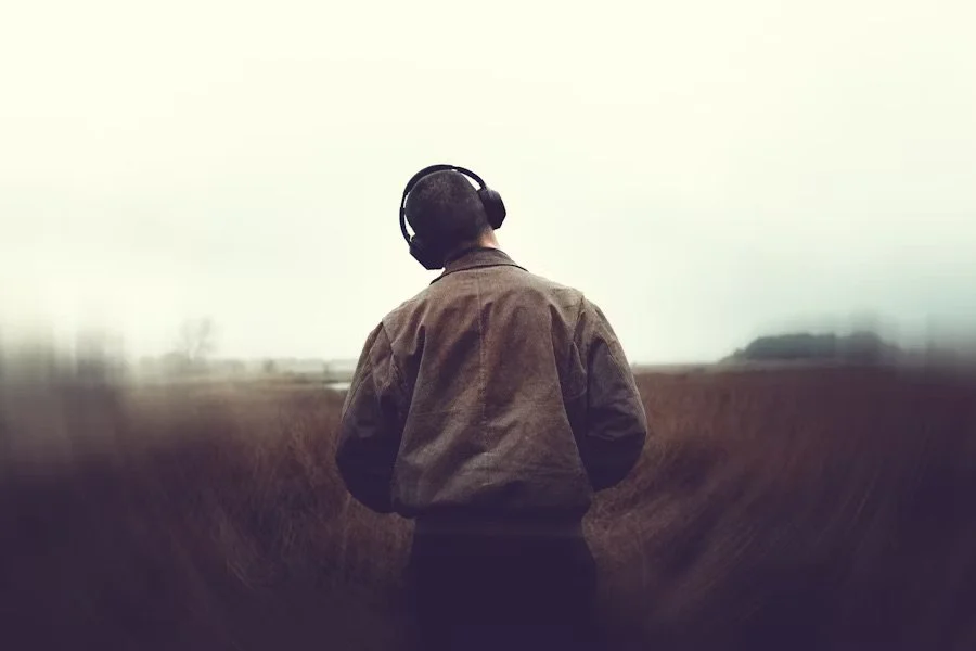 A person sitting peacefully with headphones on, surrounded by natural light and soft decor, symbolizing the calming and therapeutic effects of music on mental health and emotional well-being.