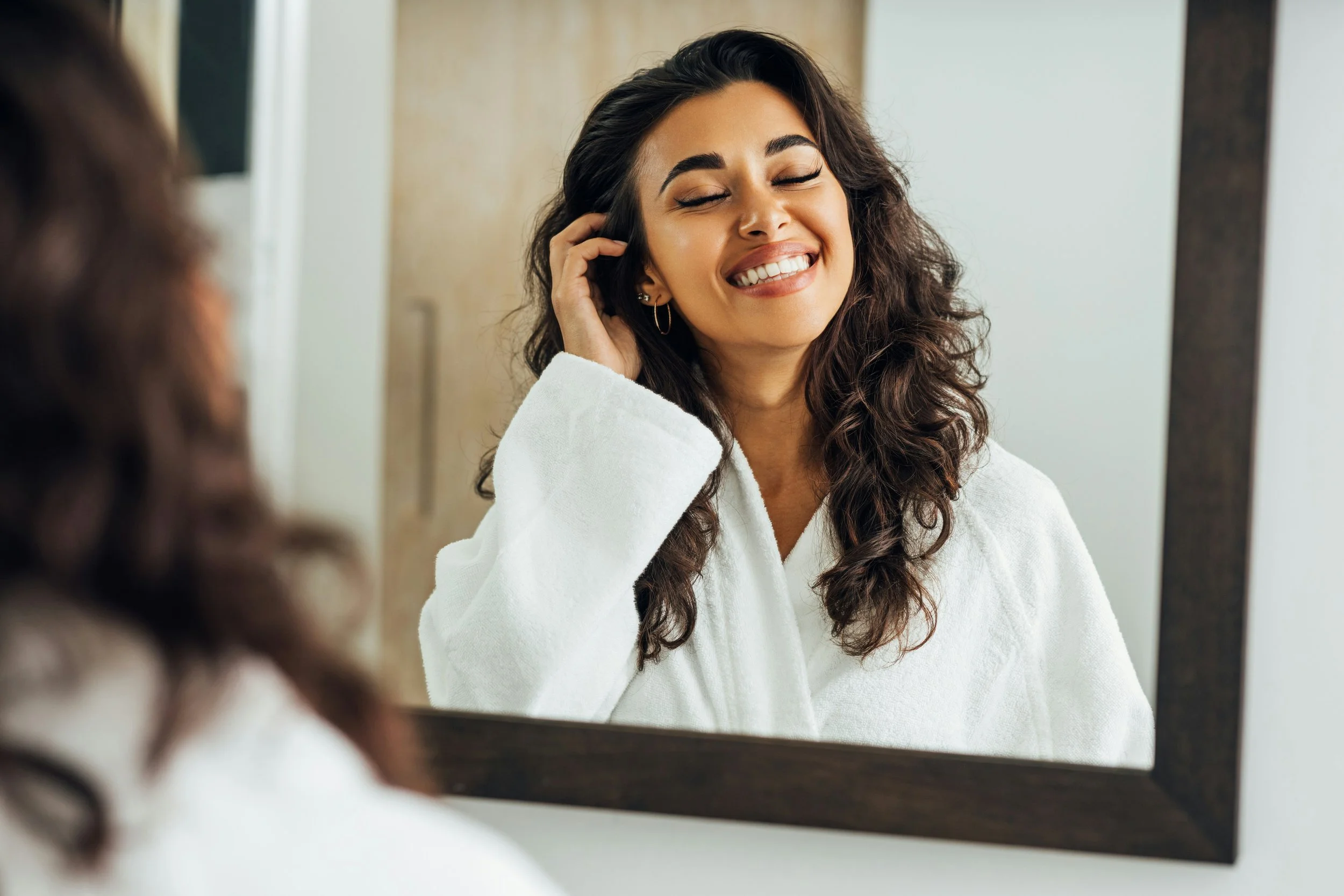 Confident young adult looking at their reflection while exploring the psychology of glow-ups, self-esteem, identity, personal growth, body image, and confidence