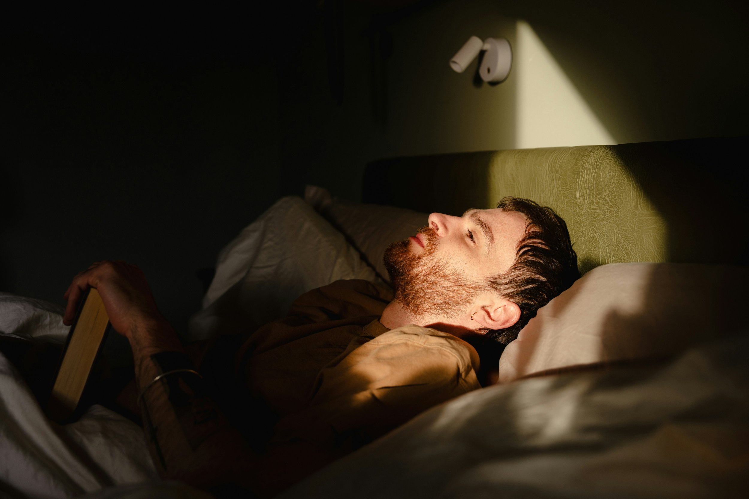 Person awake in bed at night, representing the difficulty relaxing when the nervous system remains on alert.
