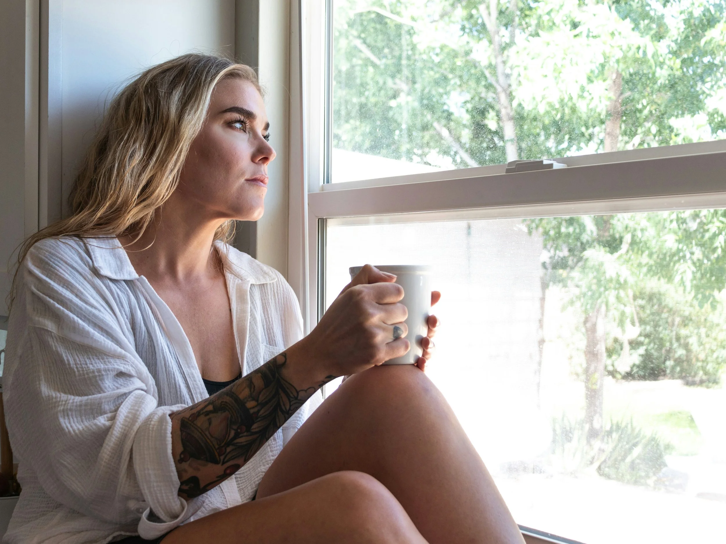 Reflective woman sitting quietly and appearing emotionally overwhelmed, representing emotional sensitivity and nervous system regulation