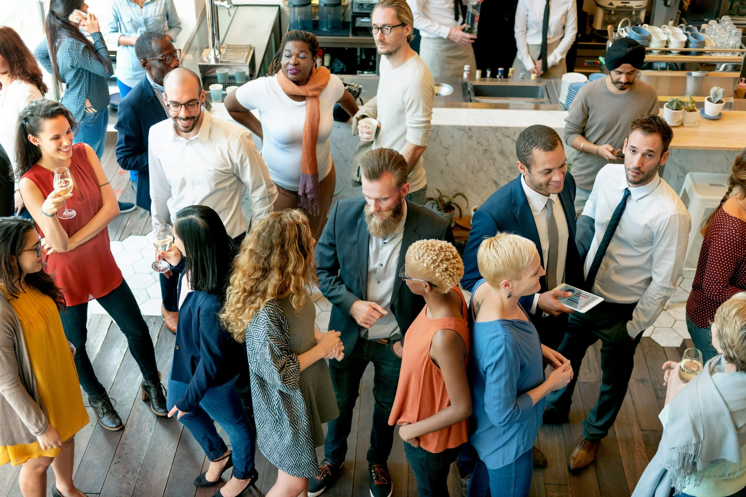 Person sitting at a social gathering and appearing lost in thought, representing the self-consciousness and anxiety that can make social situations exhausting.