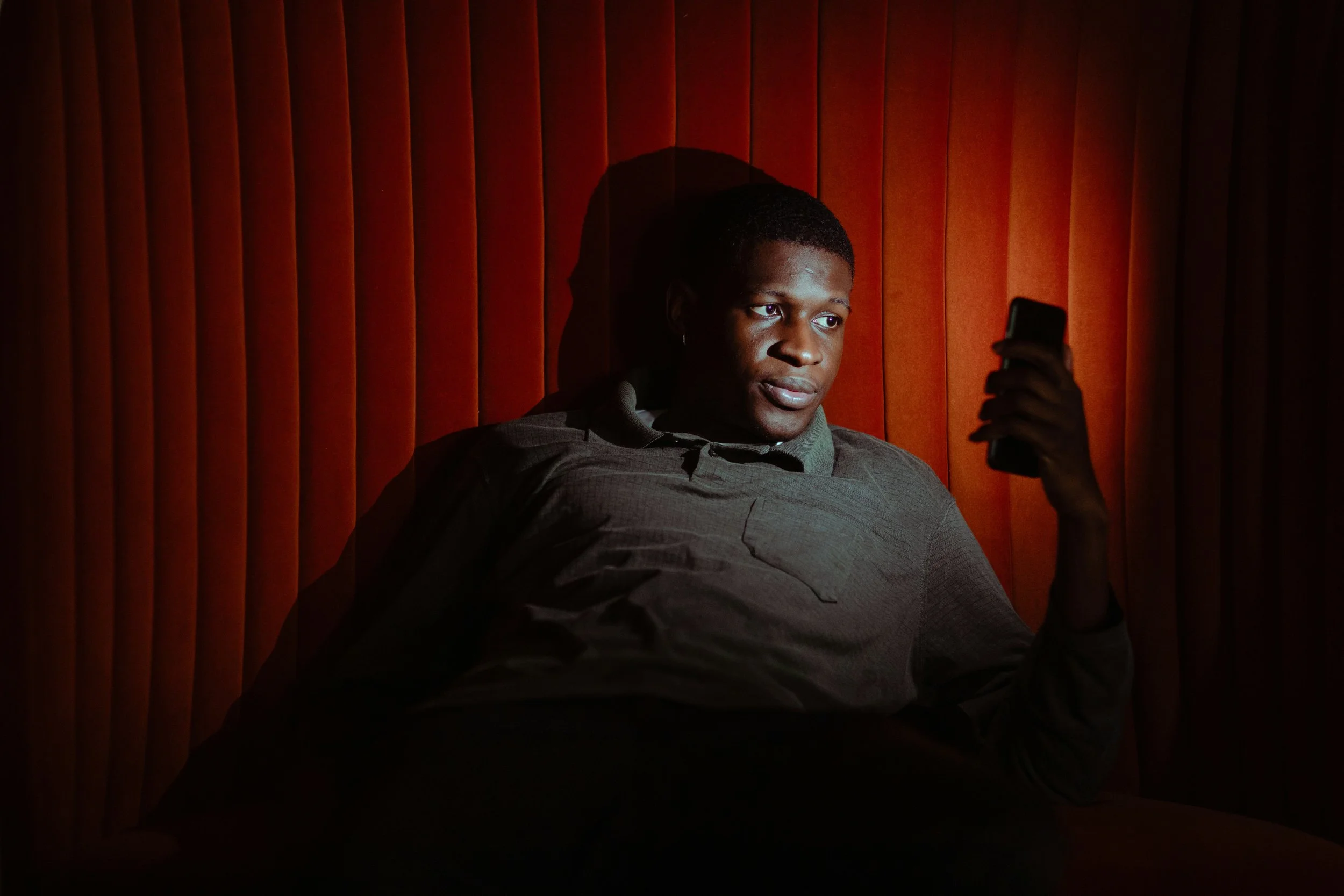 Person scrolling on a smartphone at night feeling emotionally exhausted.