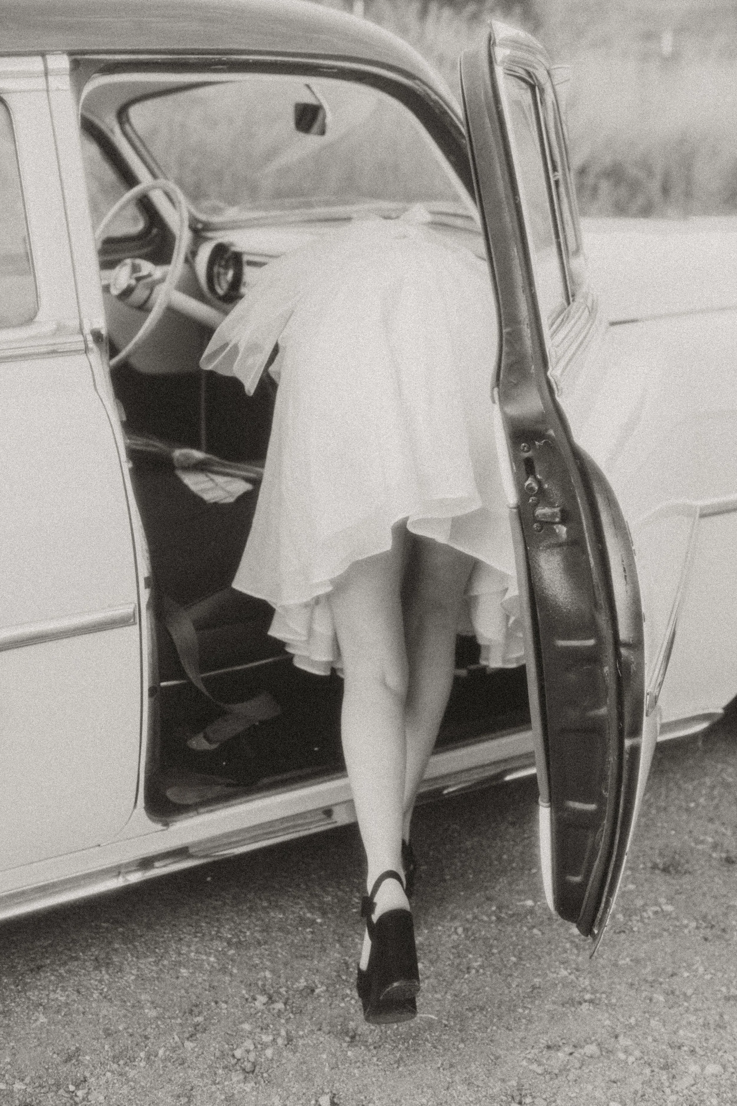Bride's dress and heels as she steps into a vintage car