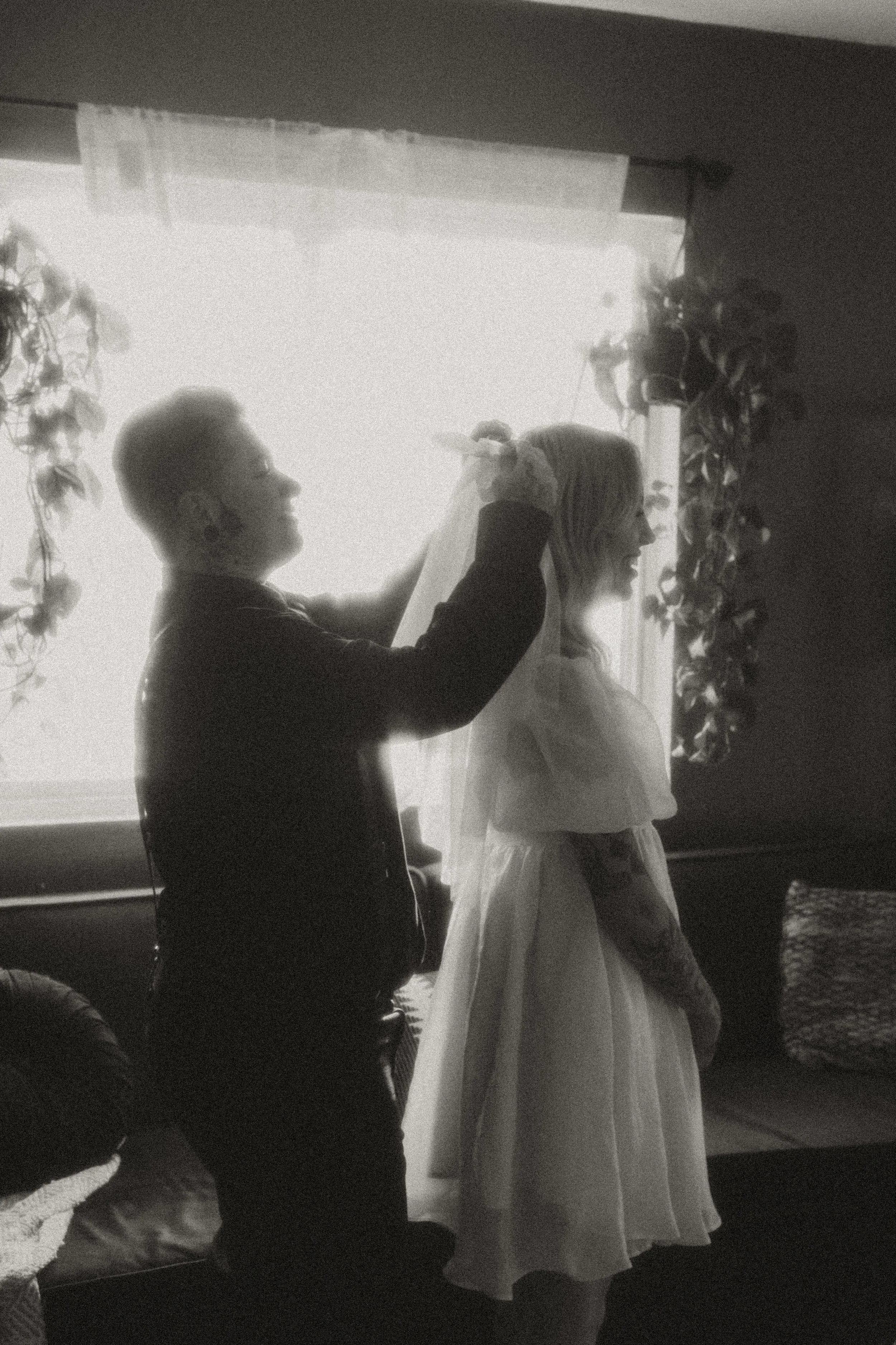 Couple getting ready together by a sunny window before their elopement