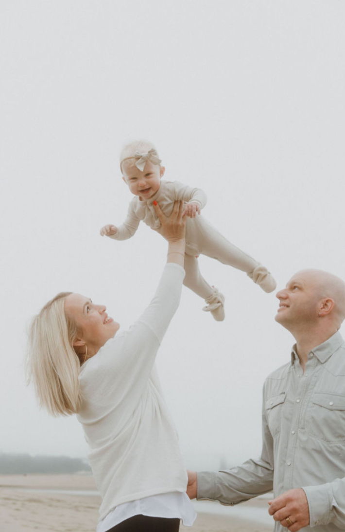 Parents tossing their laughing baby in the air during a beach family session