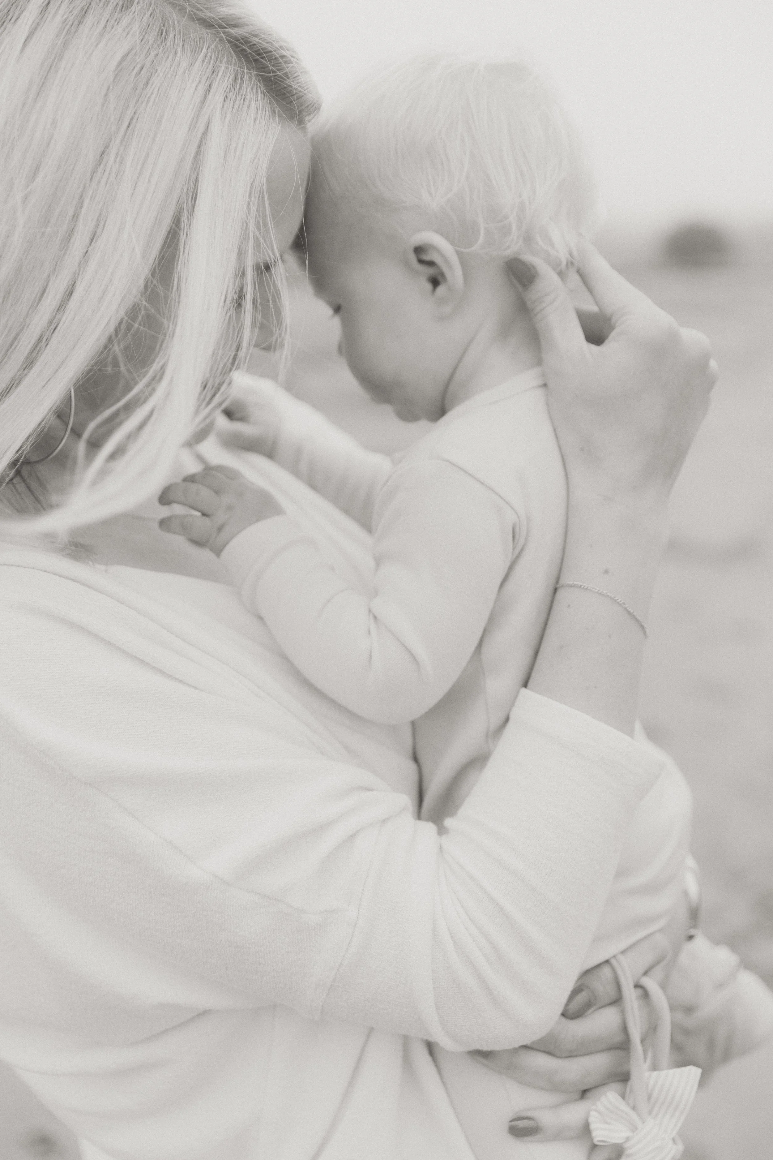 Mother holding her baby close in a soft, light-filled family portrait