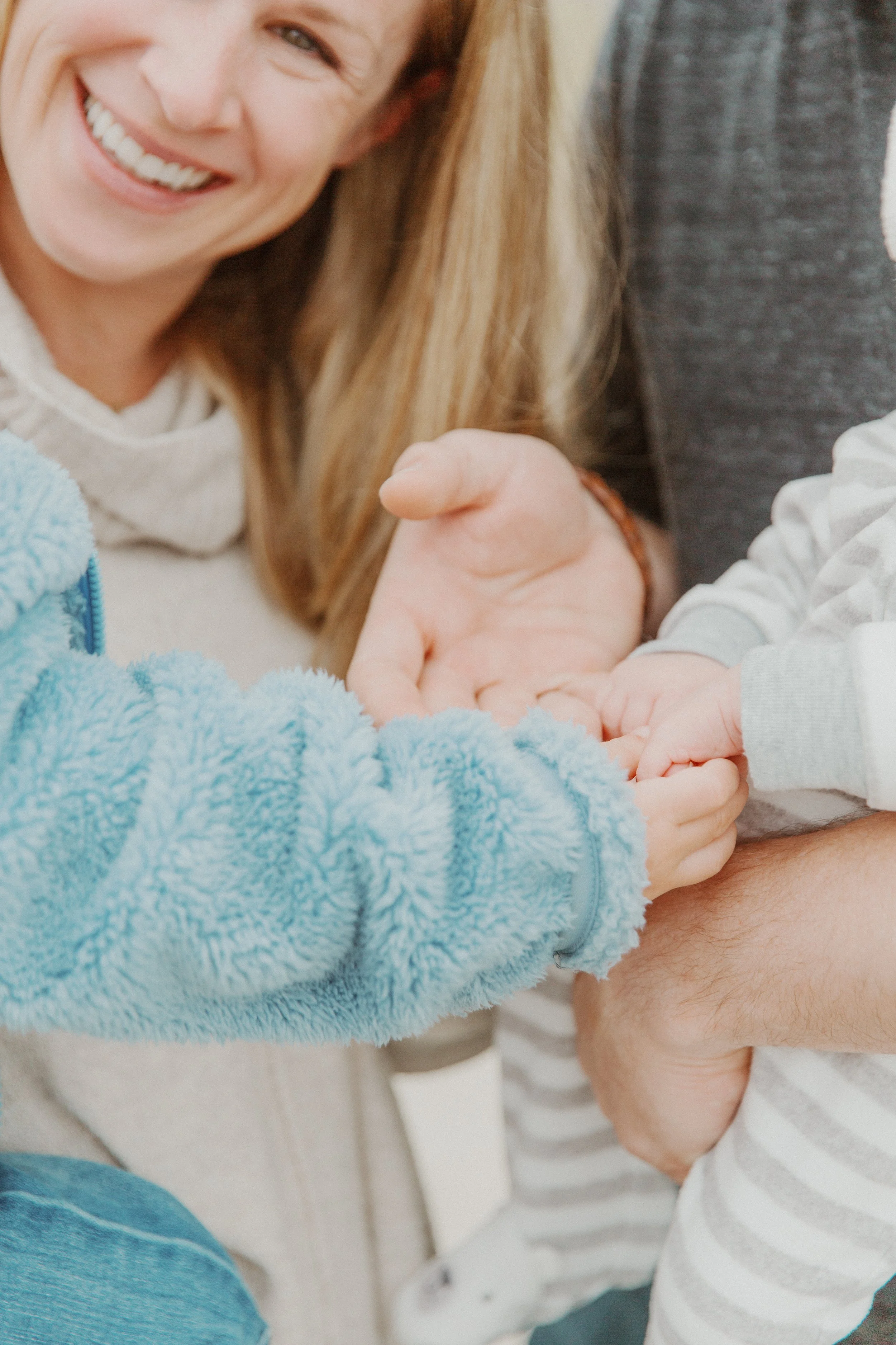 Smiling mother holding her toddler's hands during a family photo session