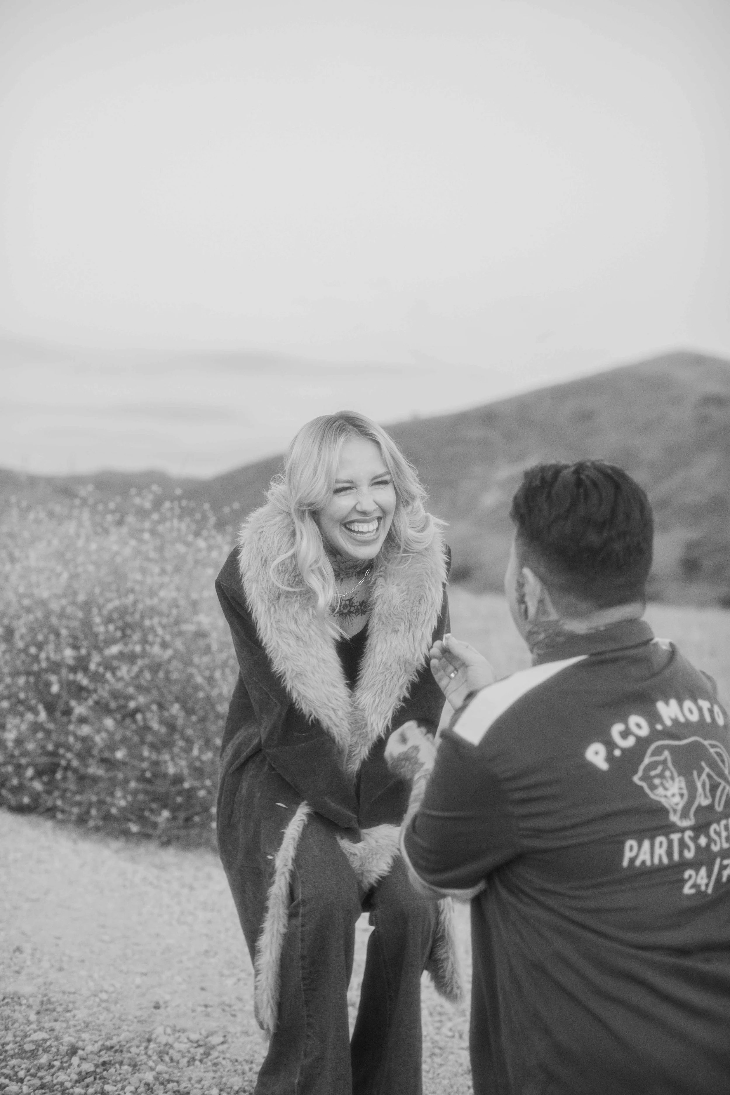 Woman reacting with surprise as her partner proposes on one knee