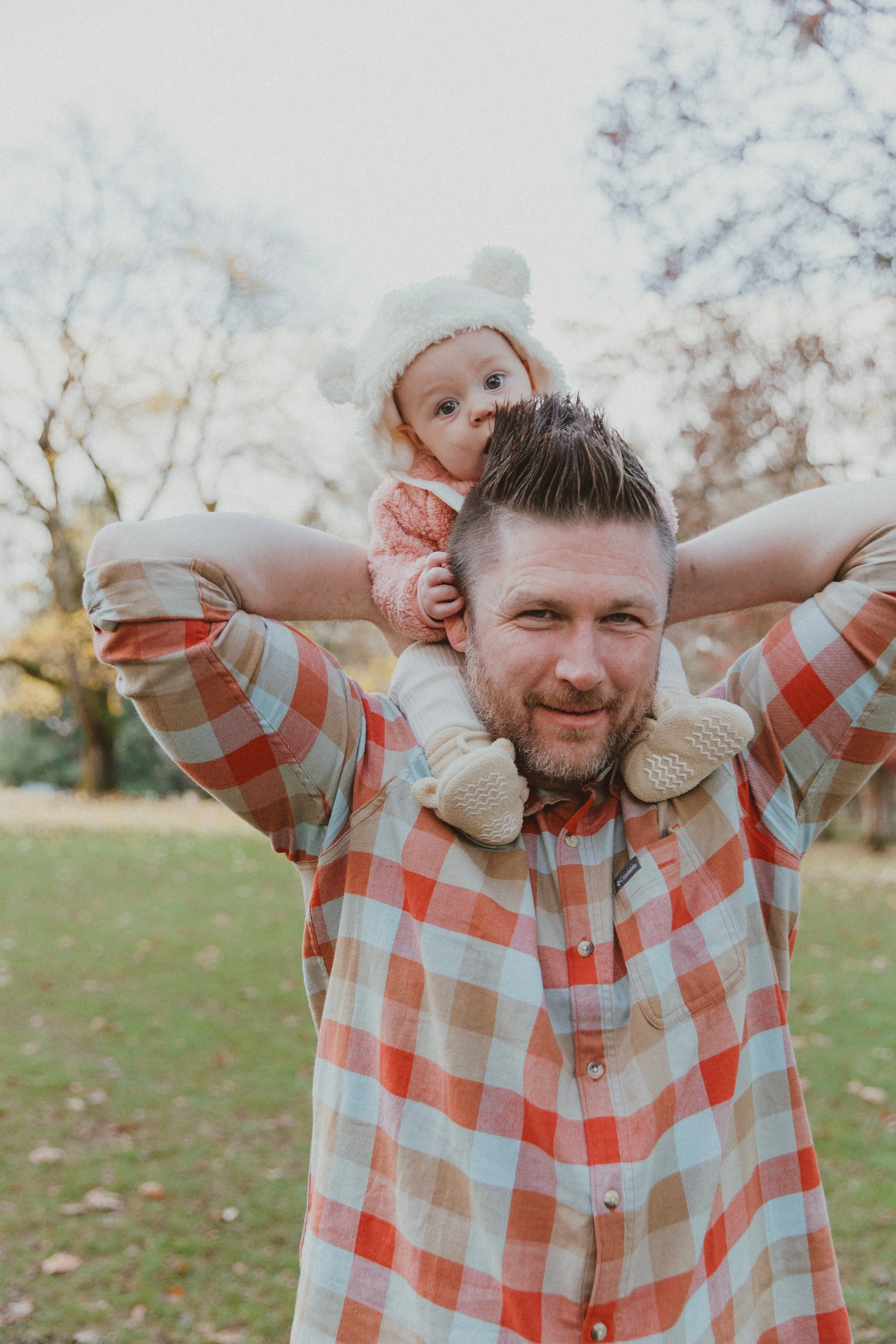 Dad carrying his baby on his shoulders in a park in the fall