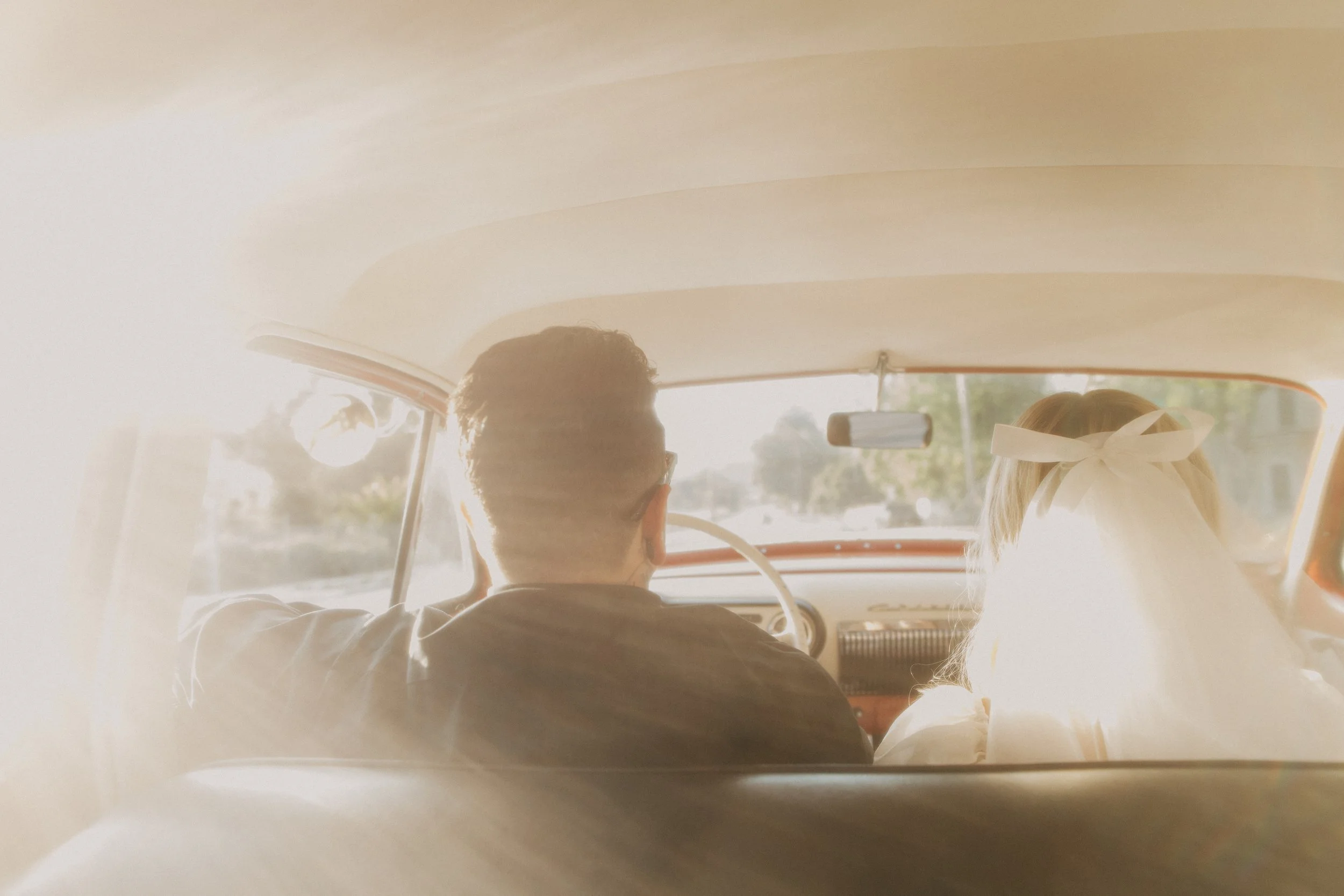 Couple riding in a vintage car on the way to their elopement
