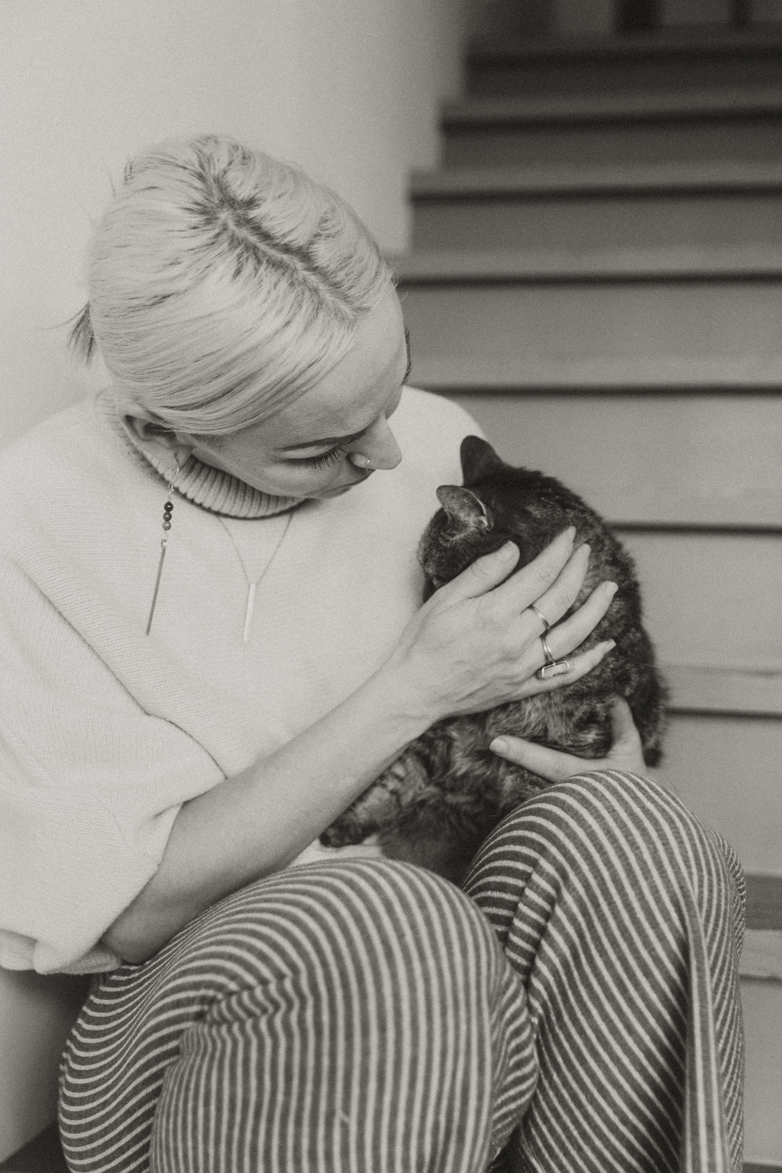 Black and white portrait of a woman in a head wrap hugging her cat