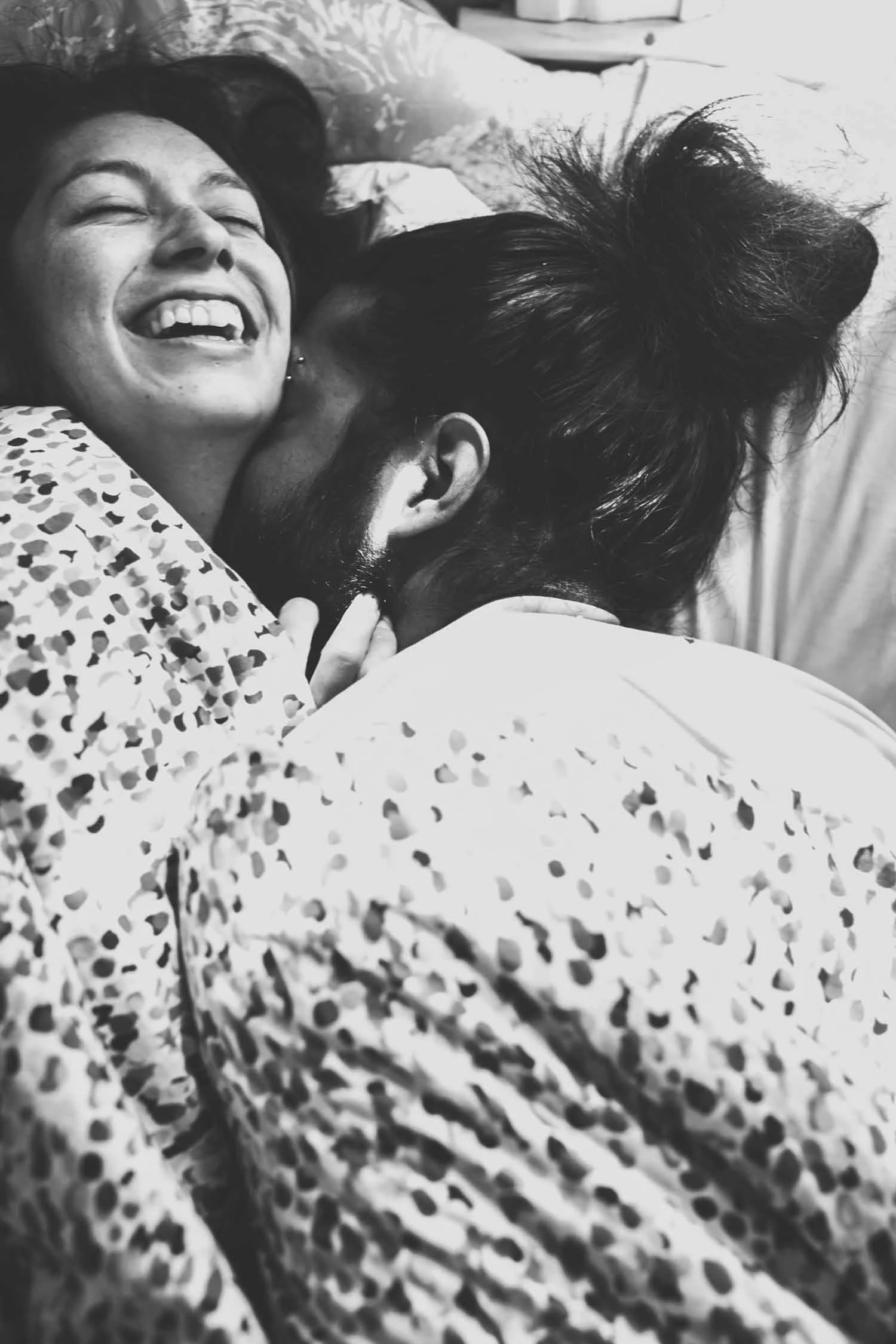 Couple laughing and cuddling close in a black and white at-home portrait