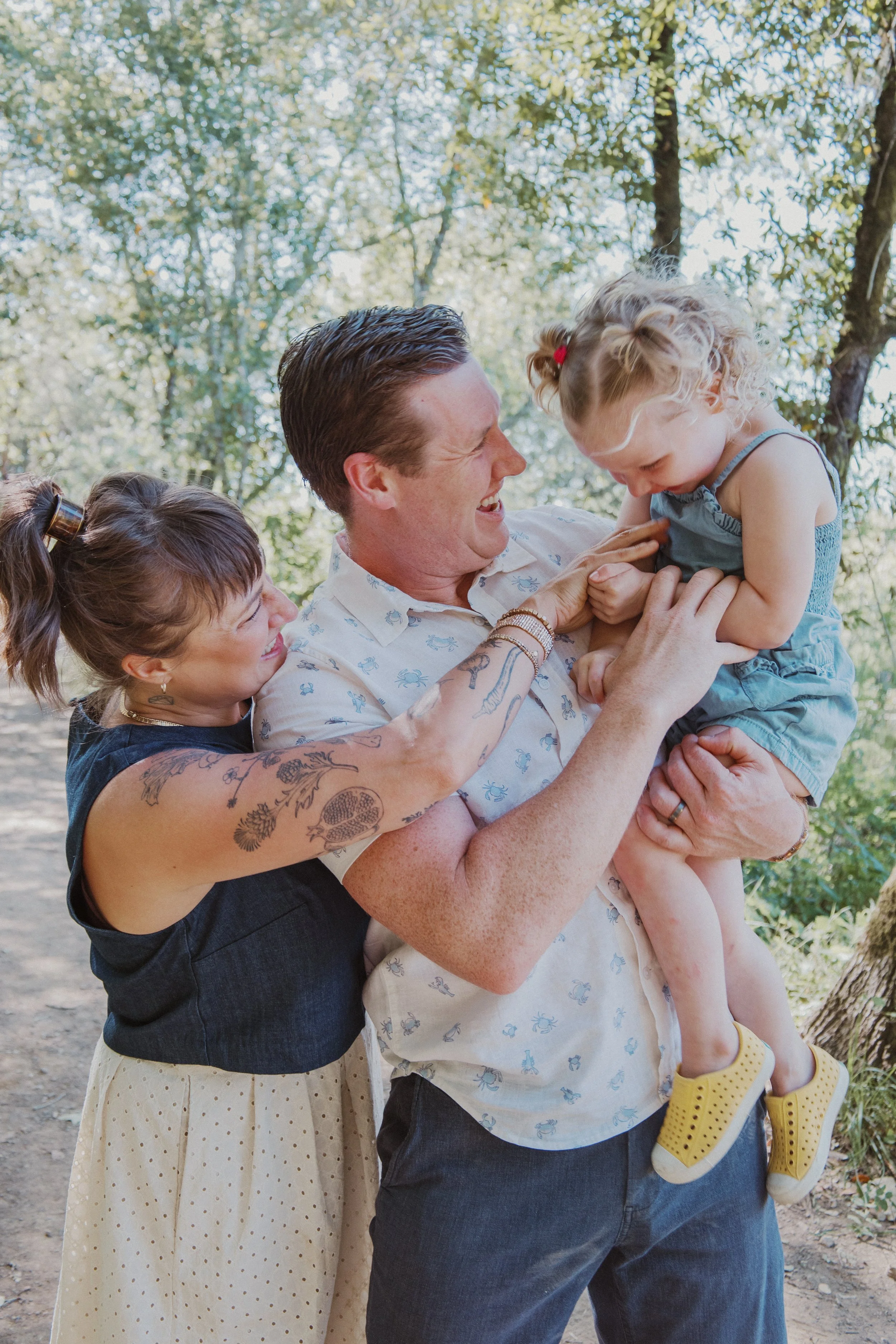 Parents laughing with their toddler on a forest trail