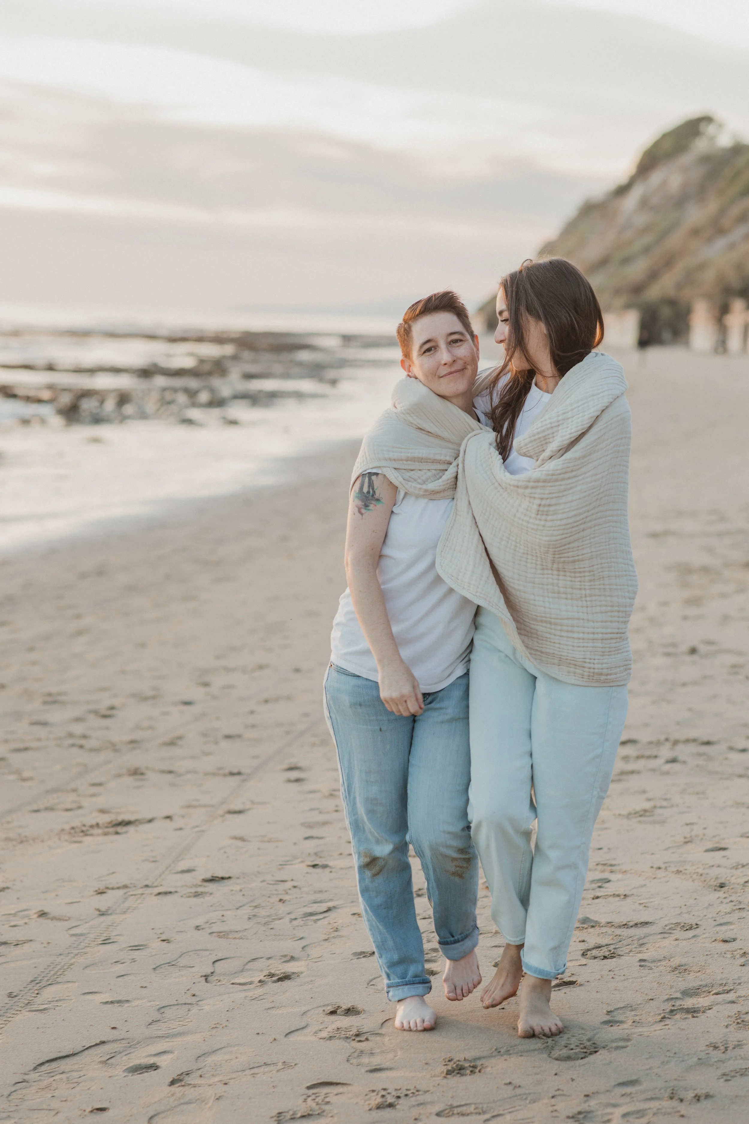 Couple sharing a blanket and hugging on the beach