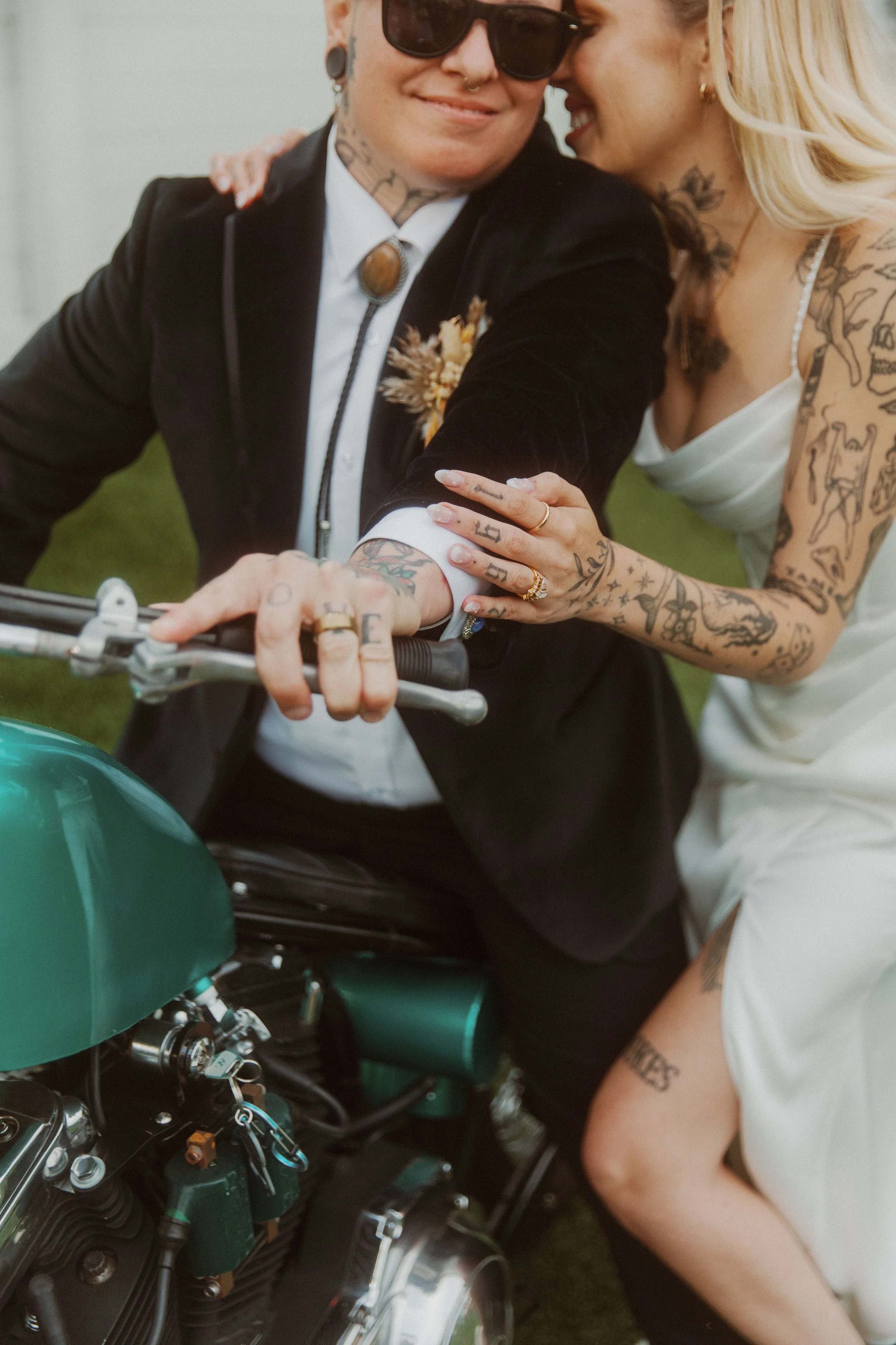 Newlyweds sitting together on a teal motorcycle