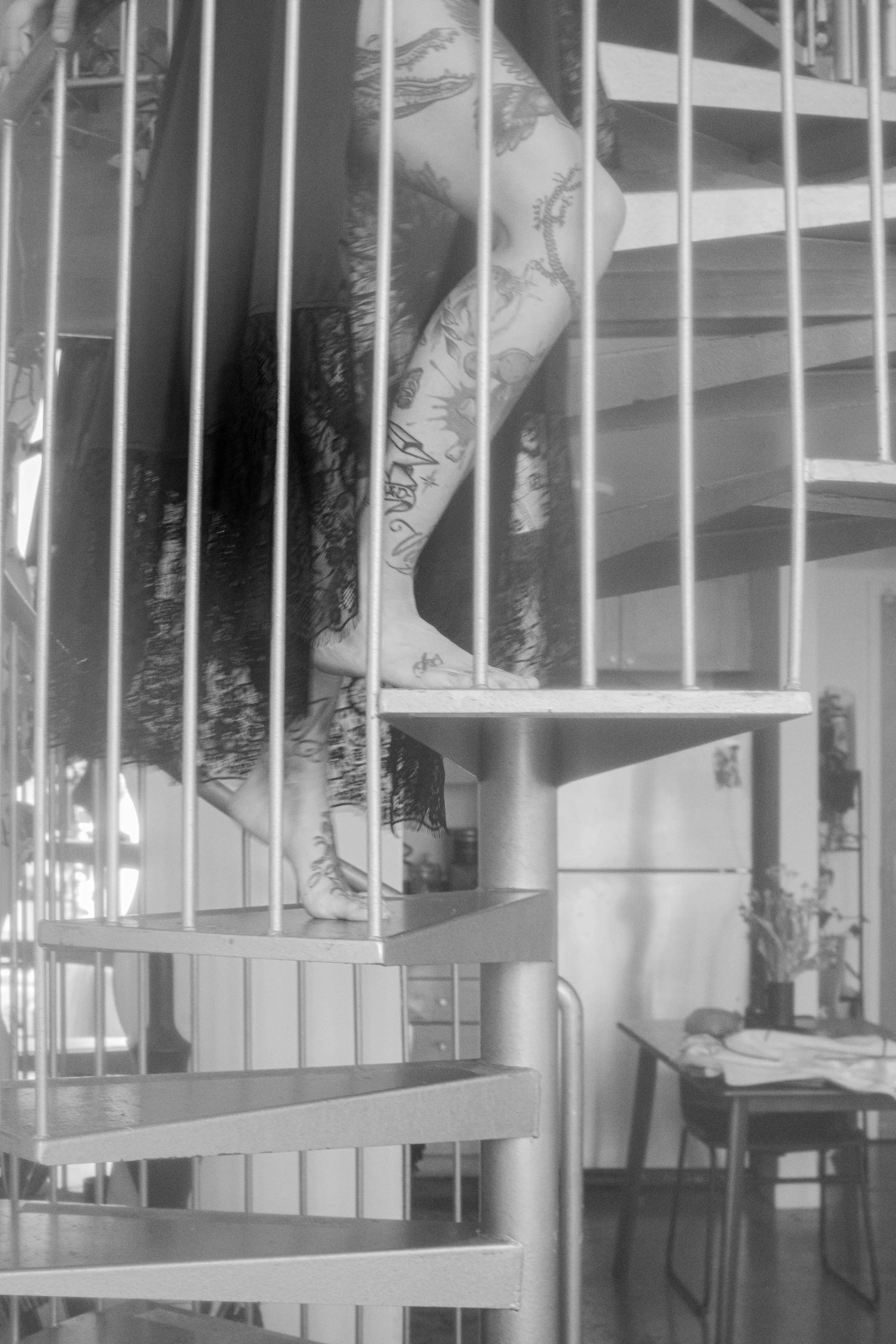 Black and white photo of a woman on a spiral staircase at home