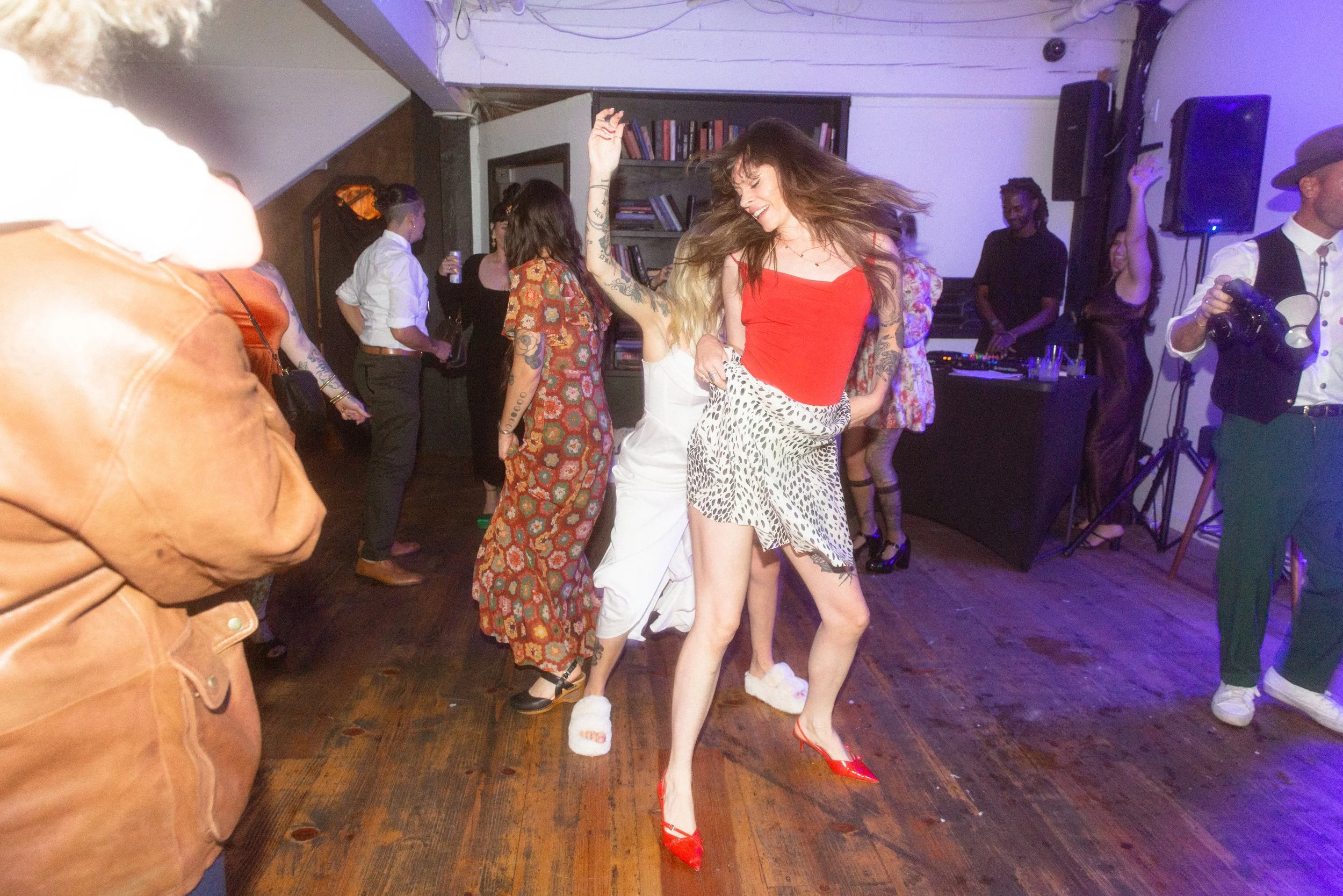 Guests dancing on a wooden dance floor under purple lights