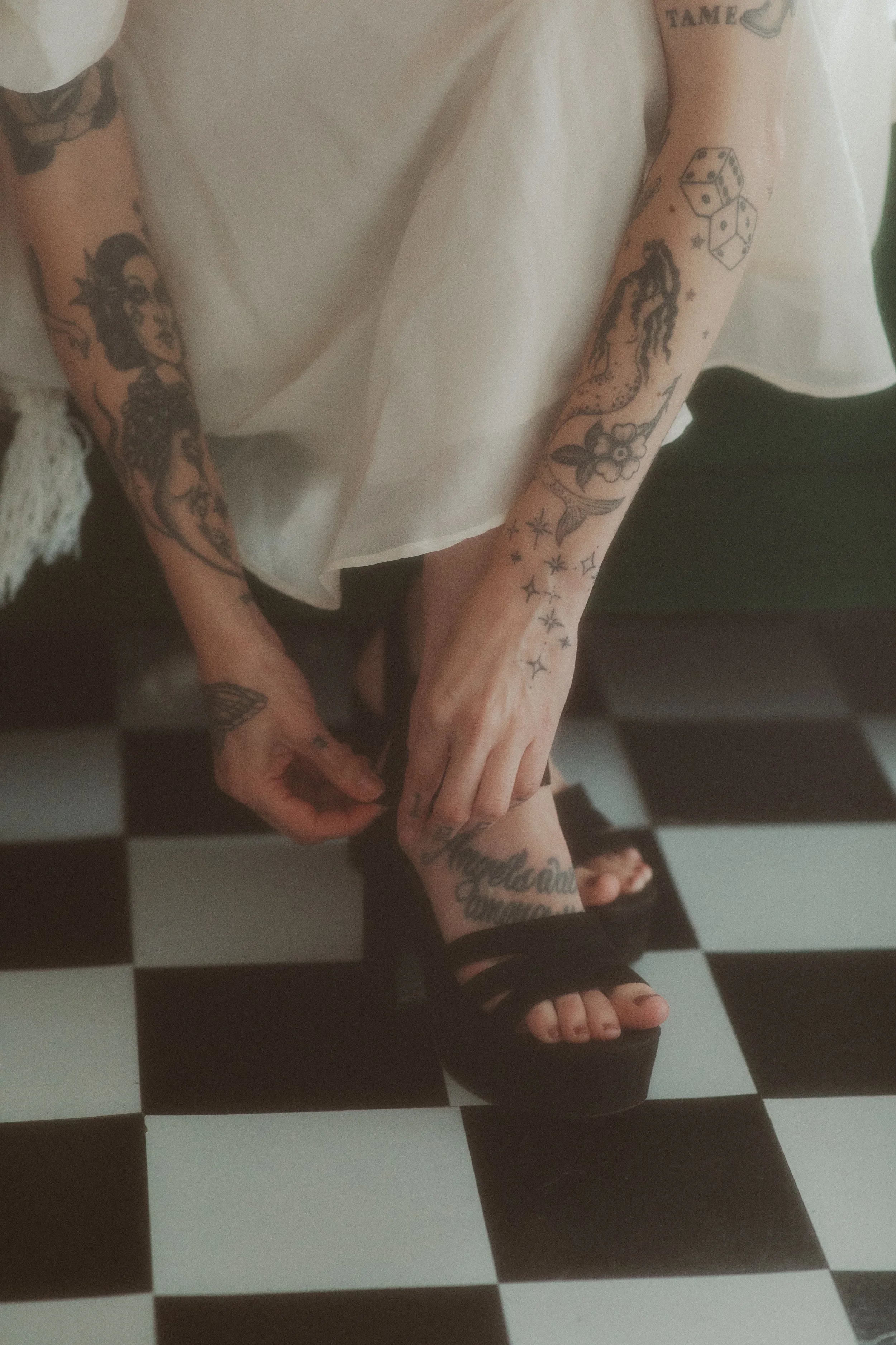 Bride buckling her shoes on a black and white checkered floor