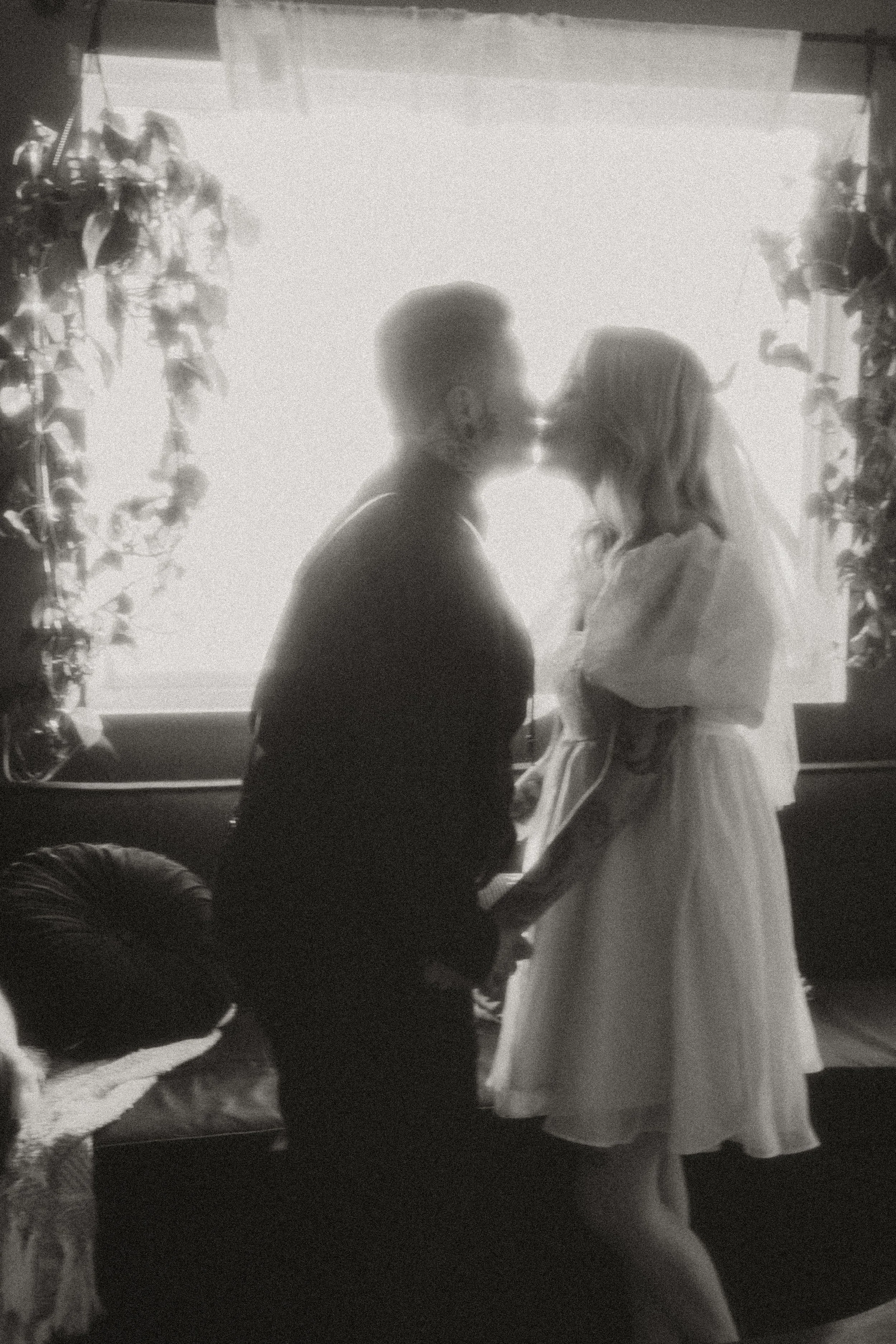 Couple sharing a kiss in a plant-filled room on their elopement day