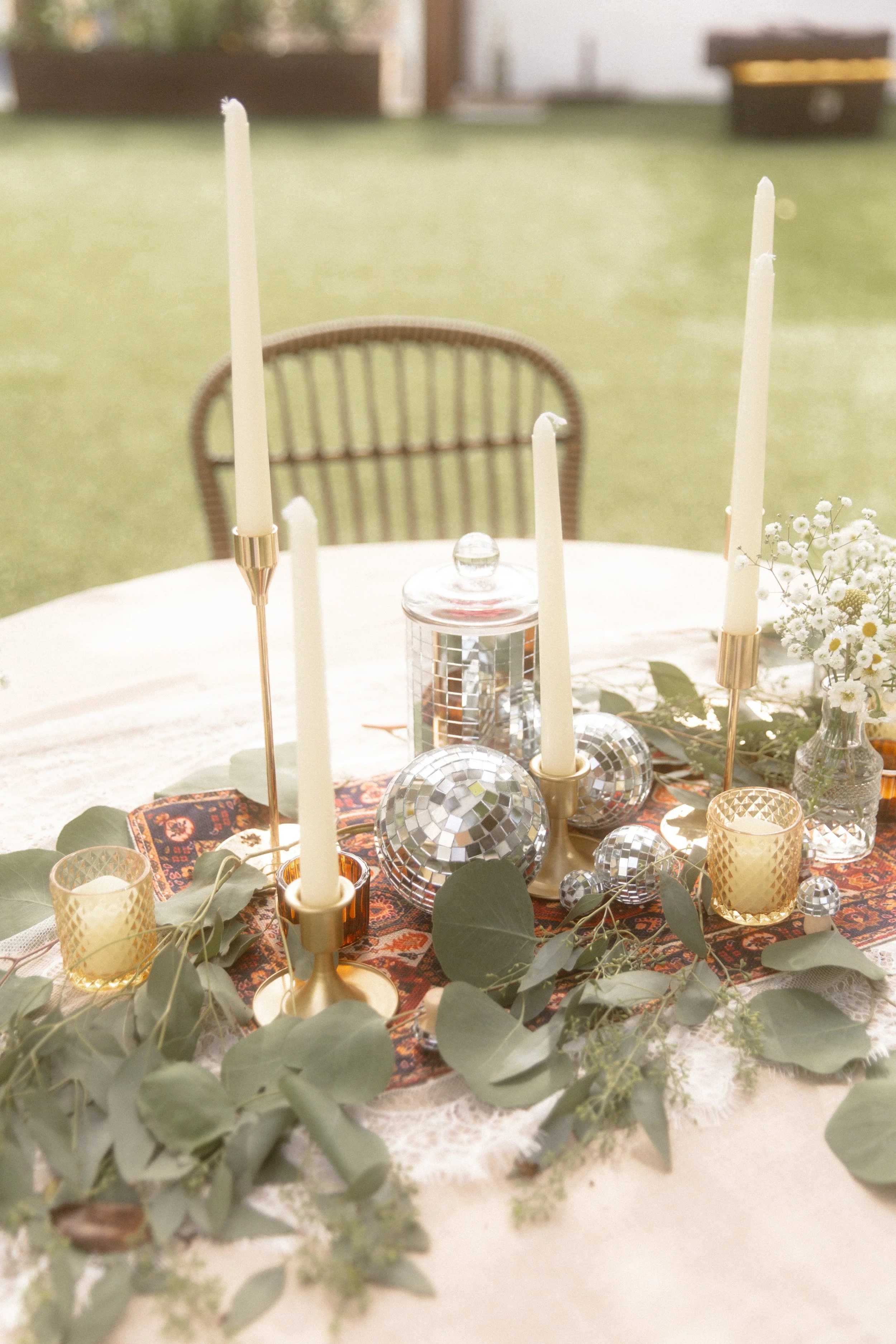 Reception table set with taper candles, disco balls and eucalyptus