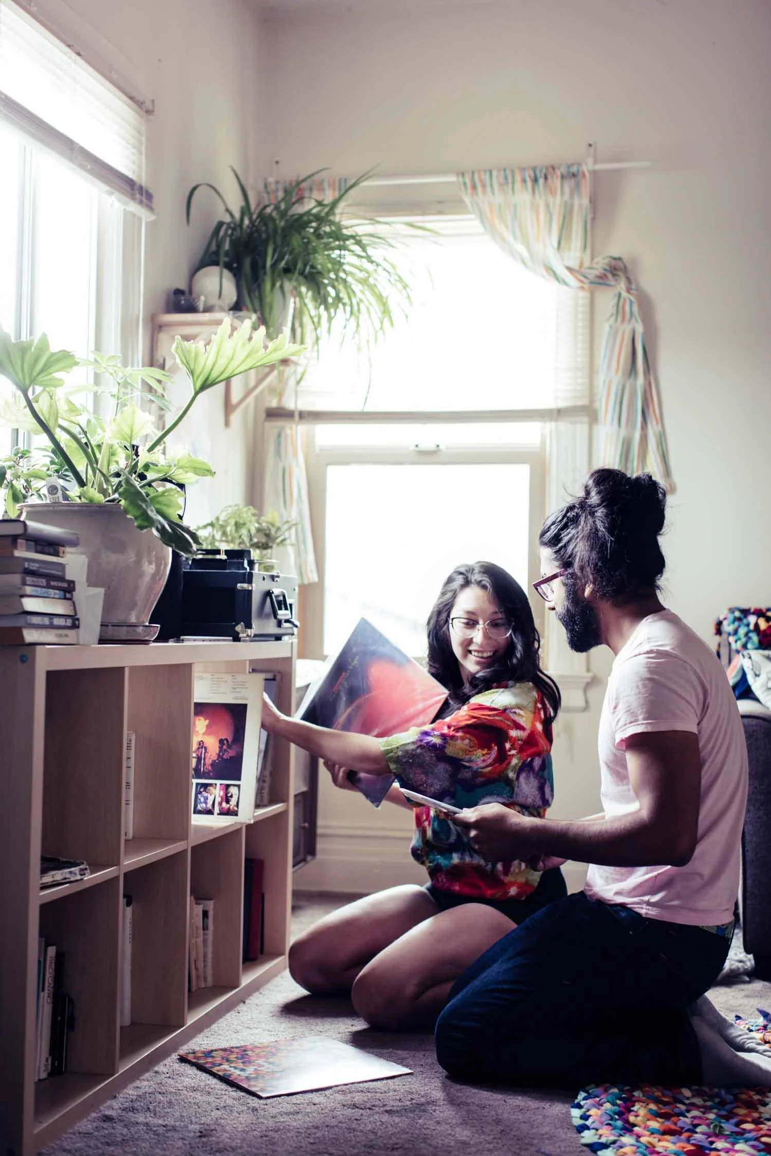 Couple sitting on the floor looking through records in a sunny living room