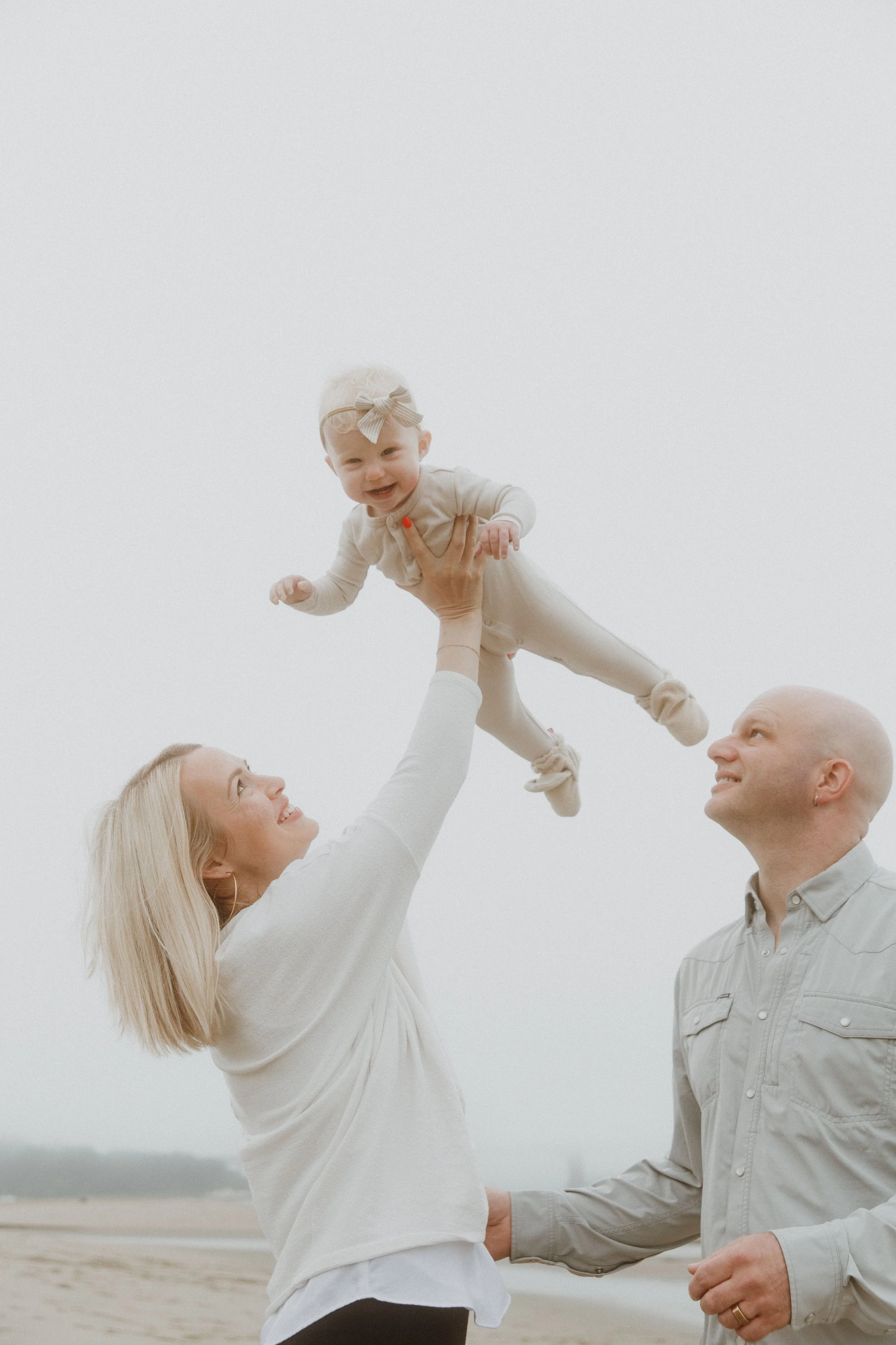 Parents tossing their baby in the air during a beach family session