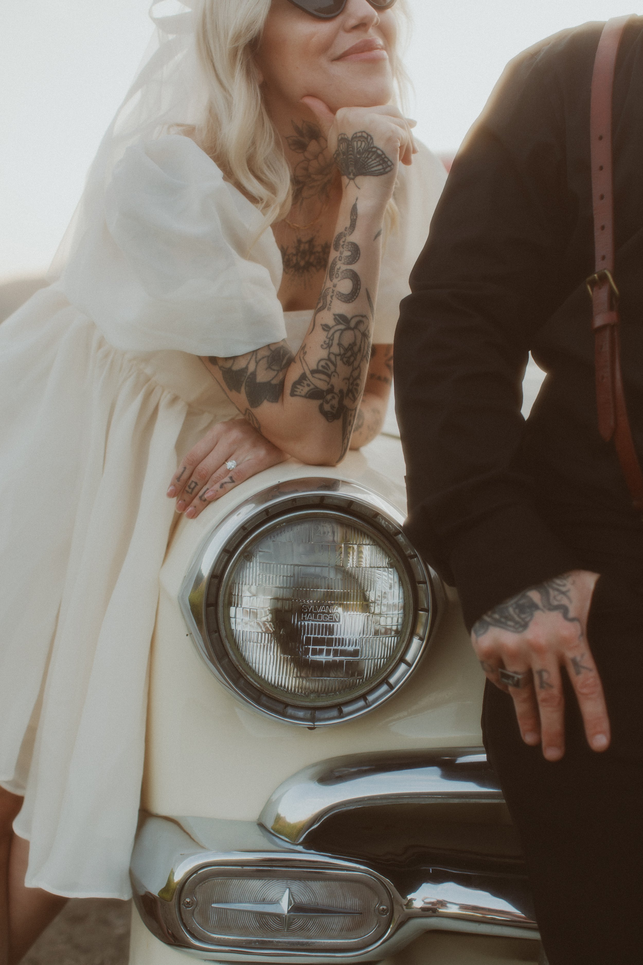 Bride leaning on a vintage car with her partner during an elopement