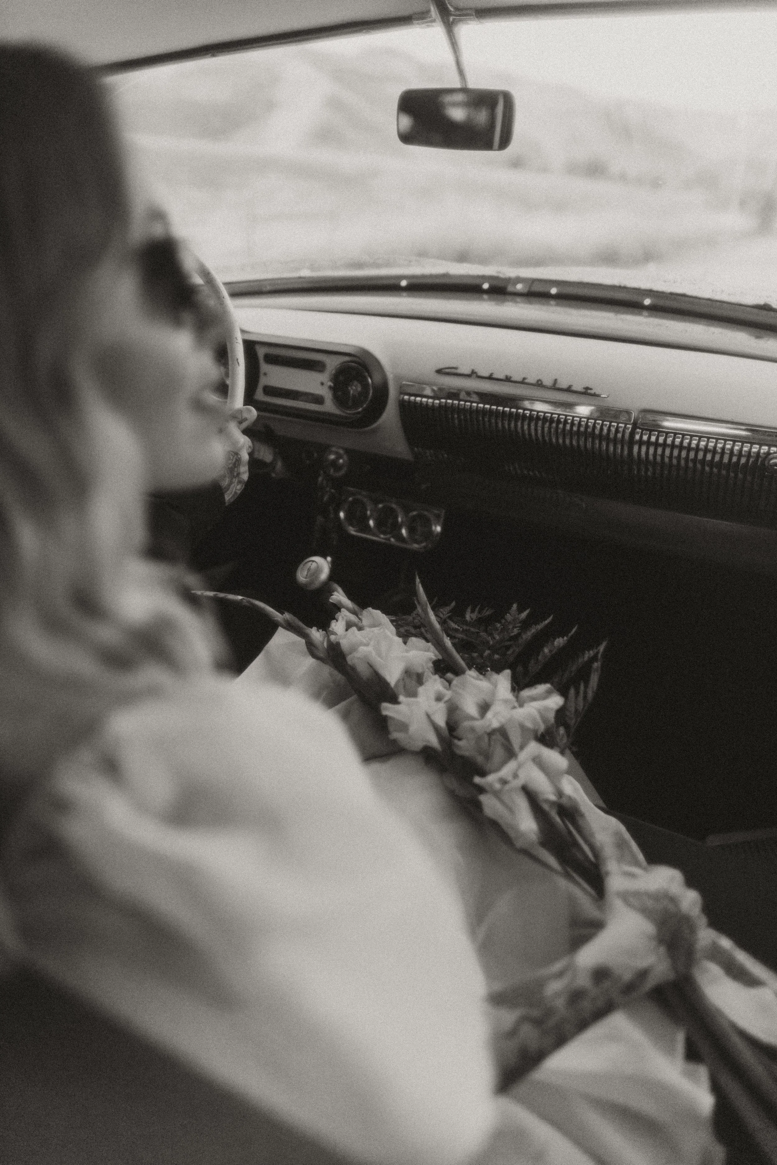 Bride holding her bouquet in the front seat of a vintage car