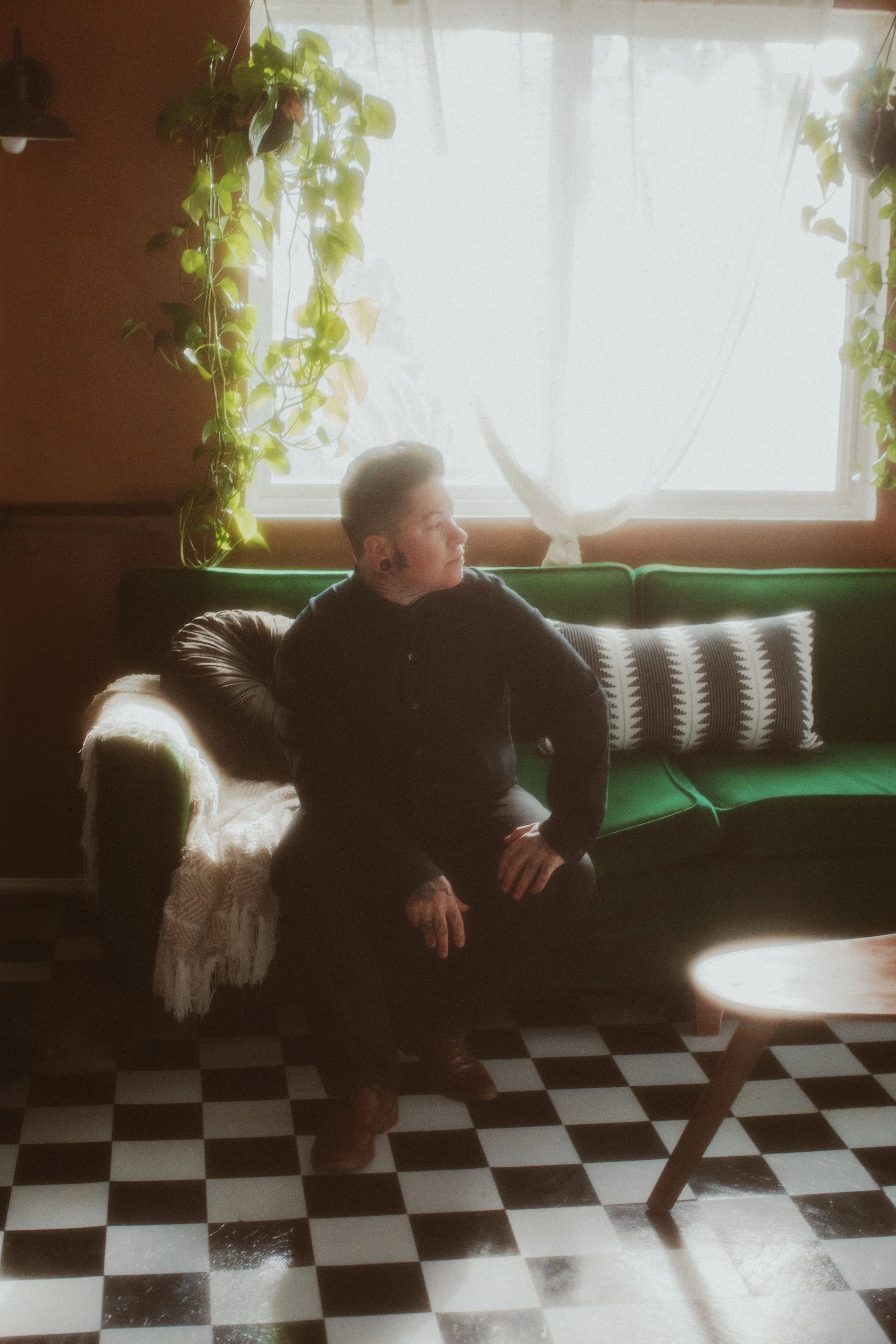 Groom relaxing on a green velvet sofa before the elopement ceremony