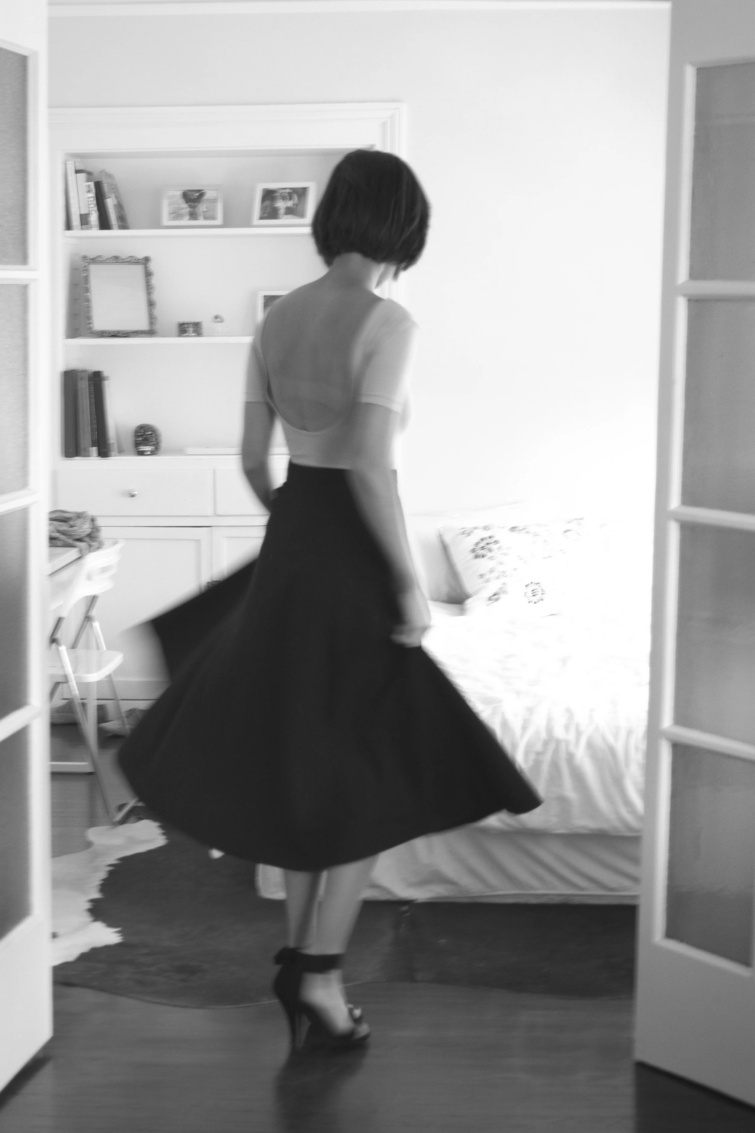 Woman twirling in a full skirt in a black and white at-home portrait
