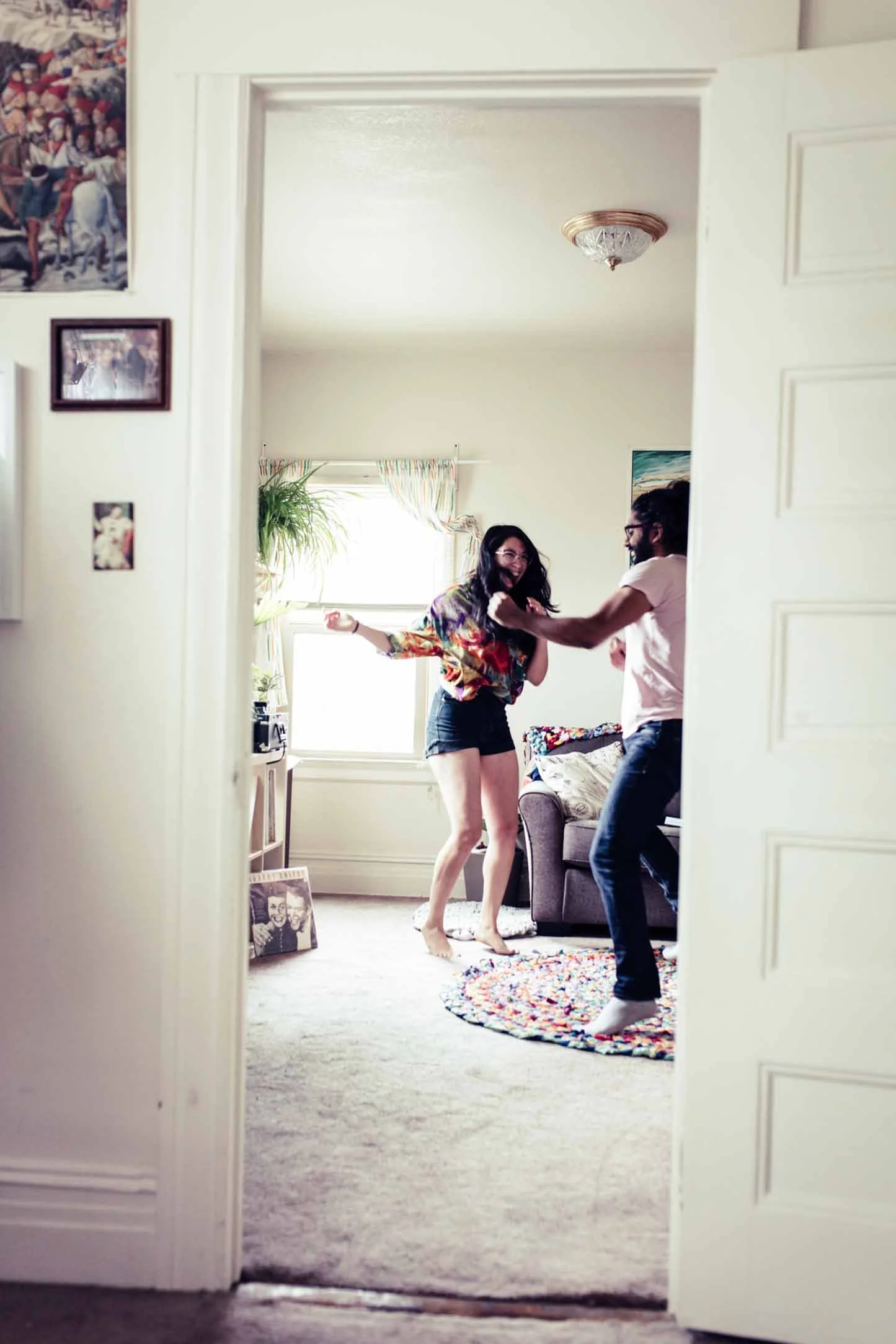Couple dancing in their living room seen through a doorway