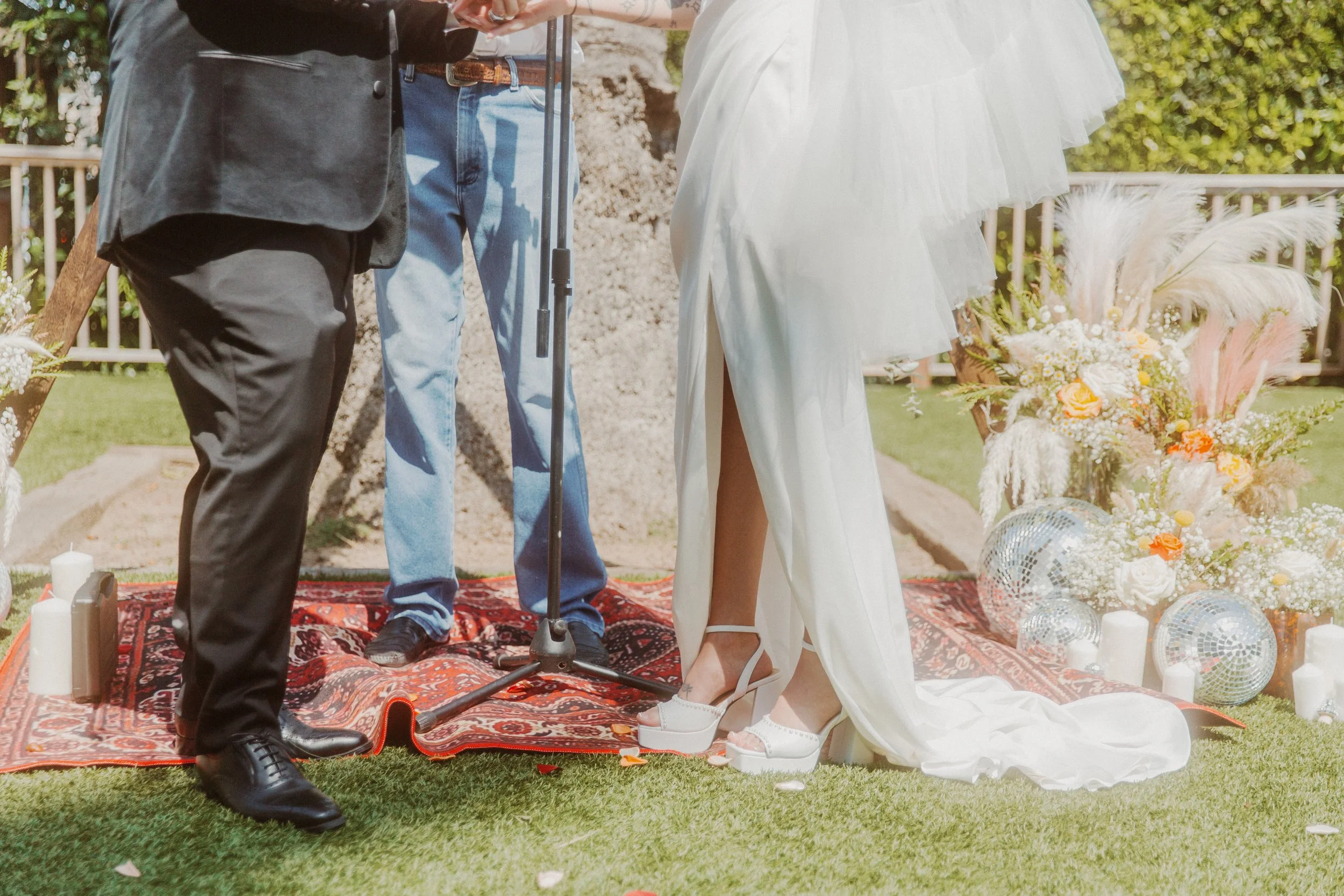 Close-up of the couple's shoes and the bride's train on a rug during the ceremony
