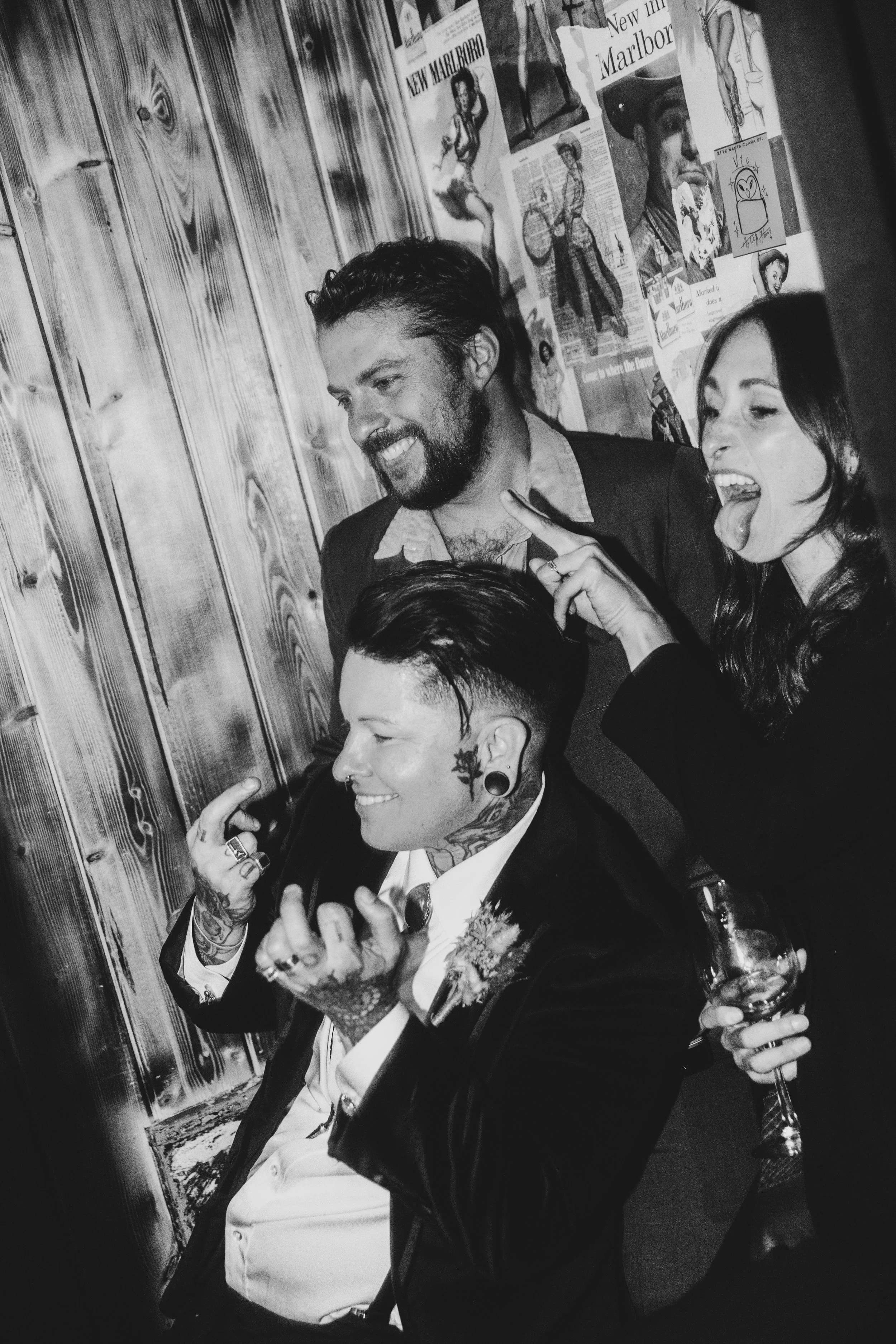 Black and white photo of a newlywed laughing with two friends at the reception