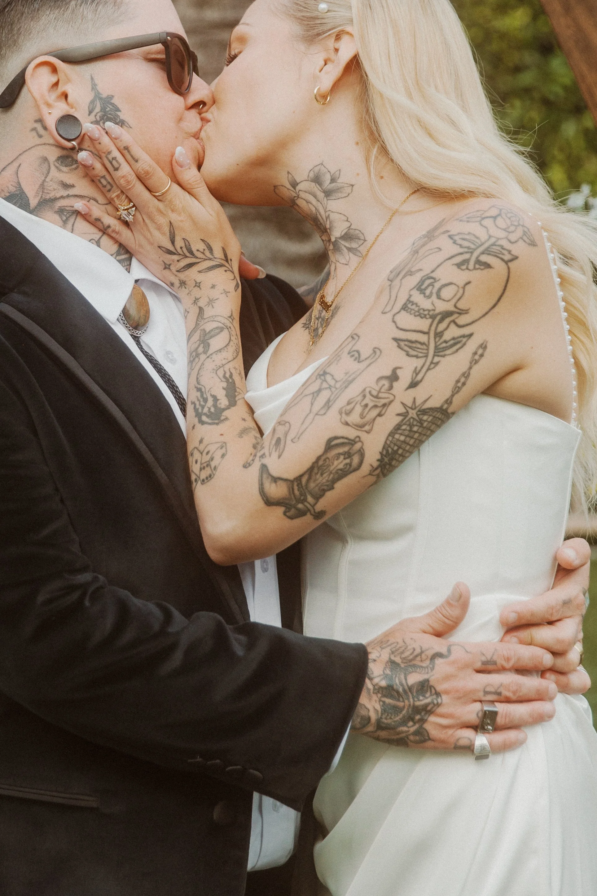 Newlyweds kissing, tattooed hands cradling a face