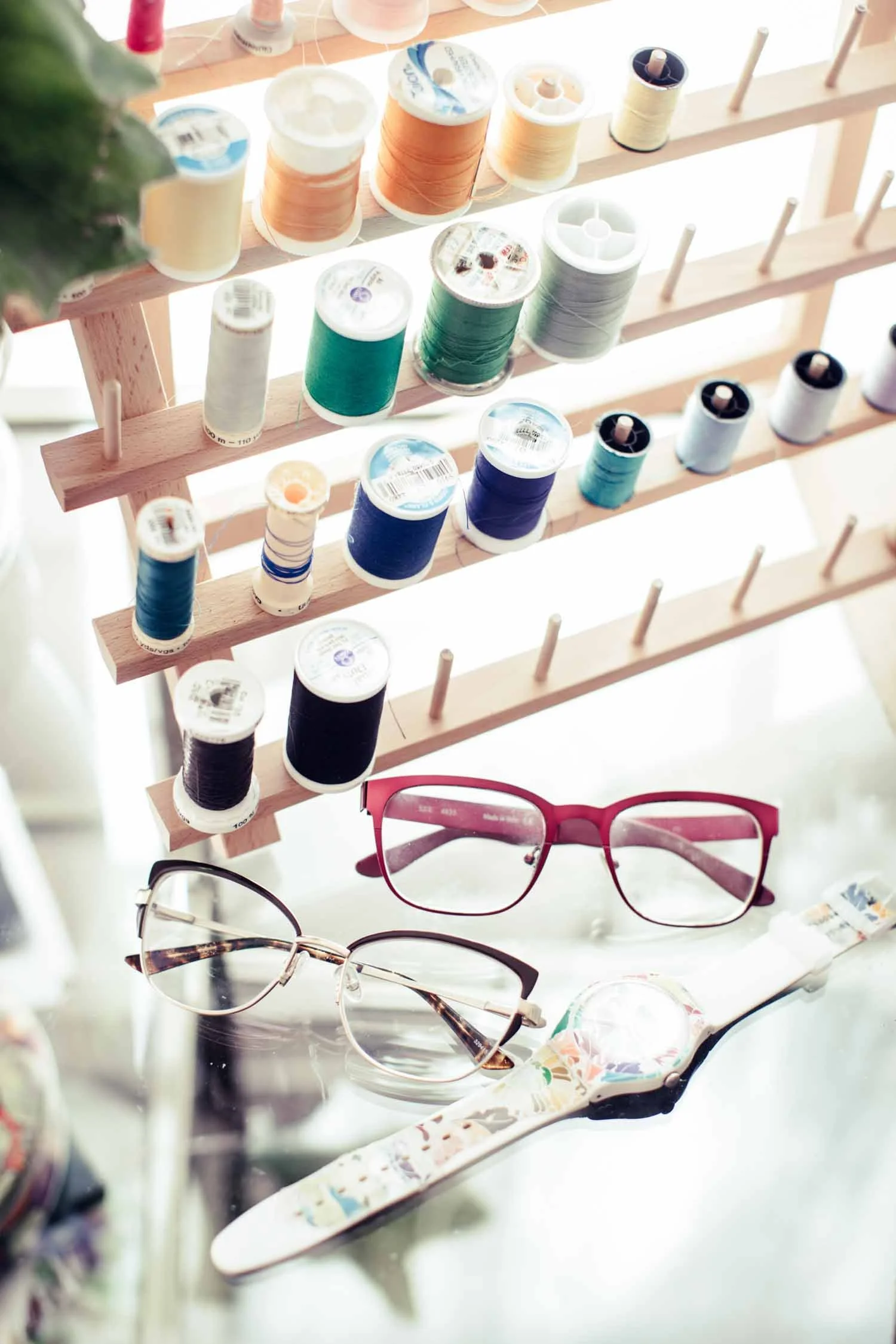 Wall of colorful thread spools and eyeglasses in a creative home studio