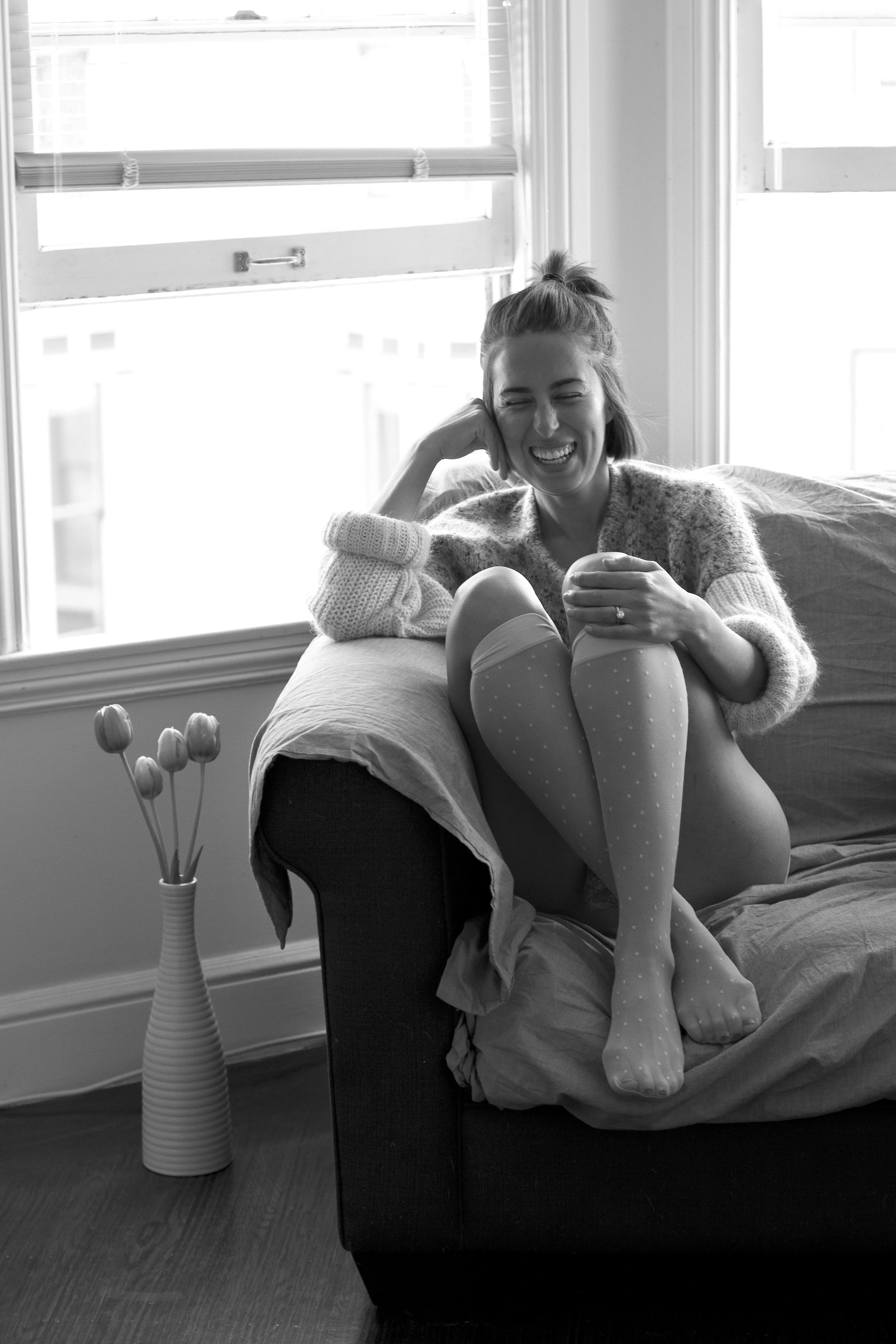 Black and white portrait of a woman relaxing in an armchair by the window