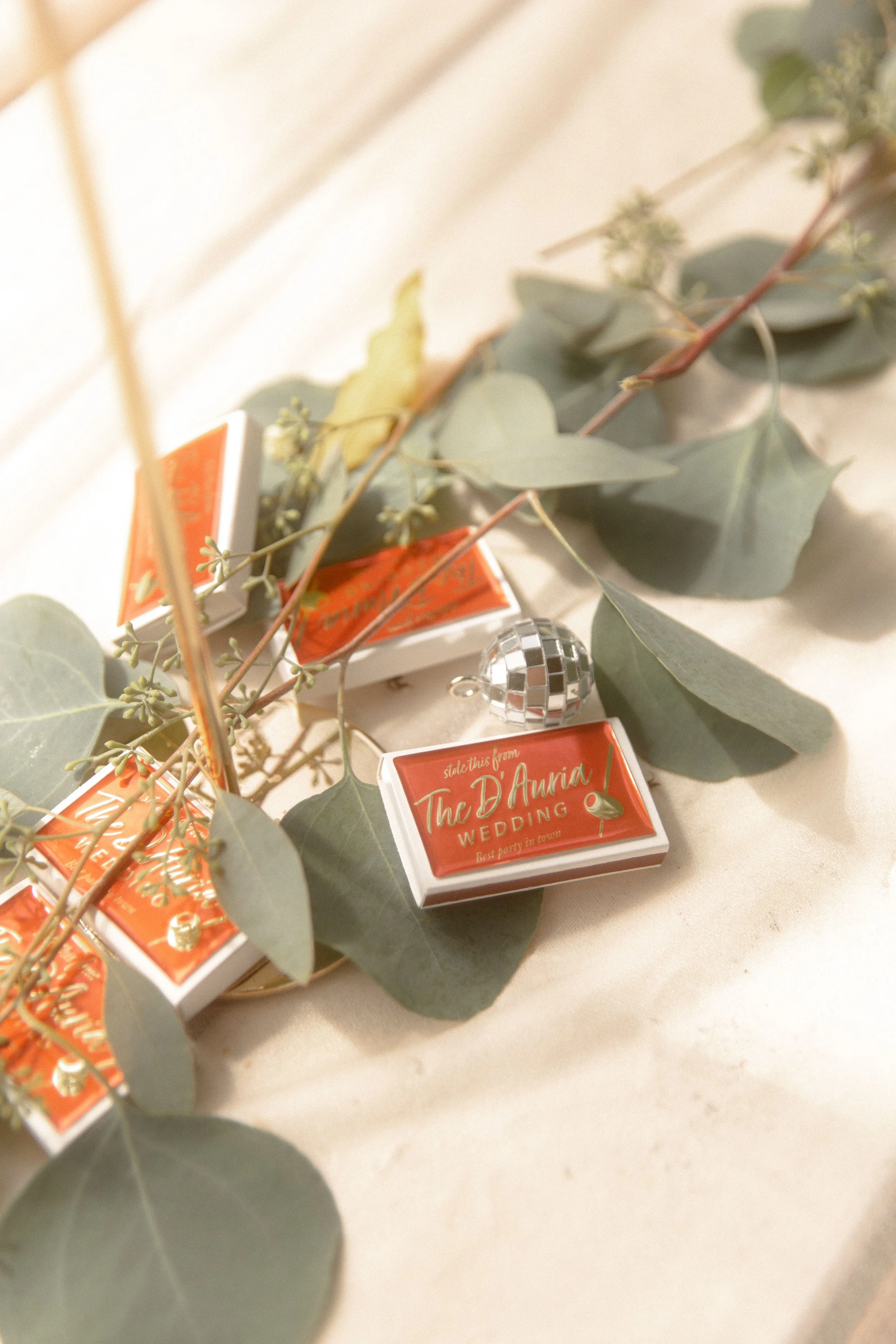 Small orange wedding favors resting among eucalyptus leaves