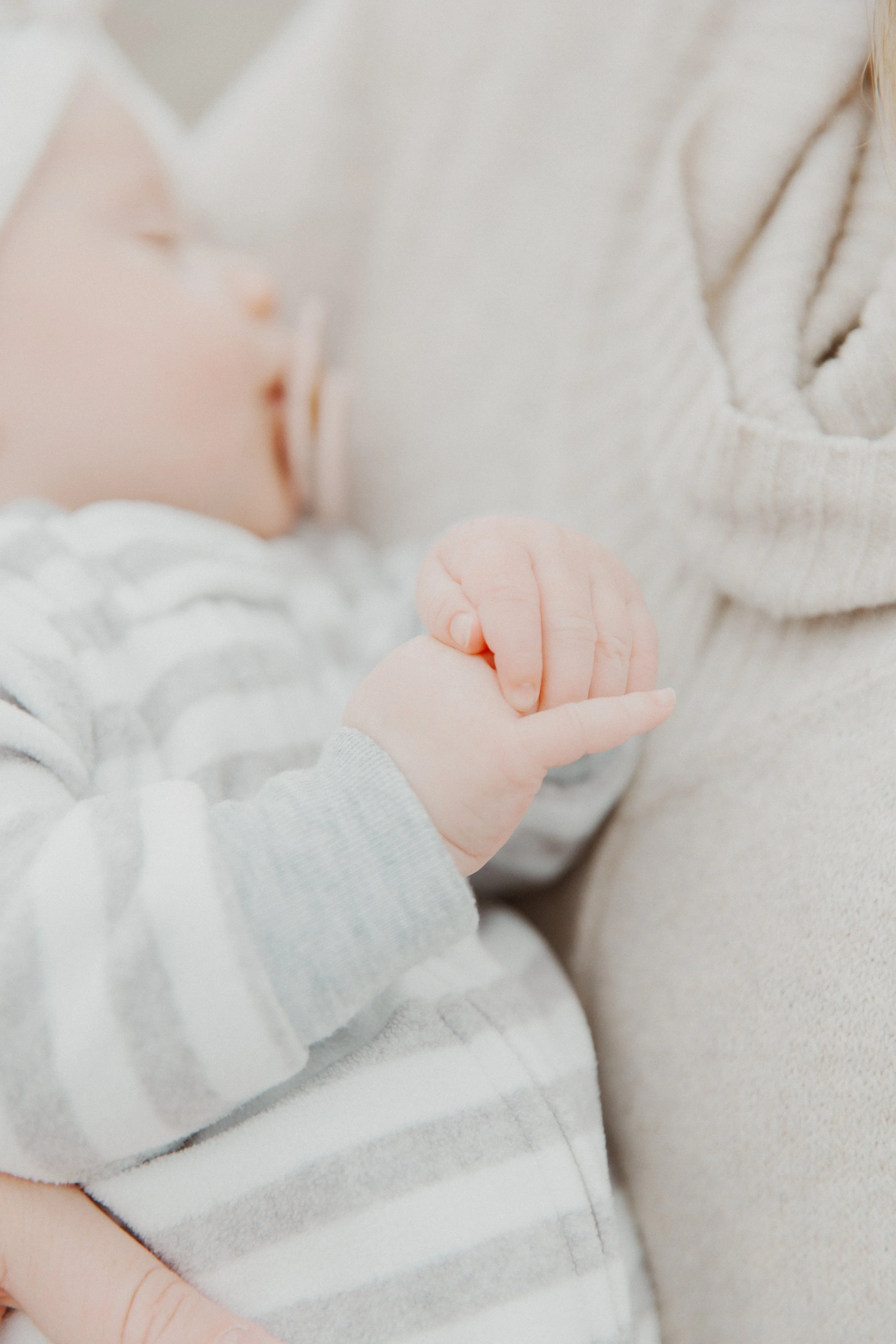 Soft close-up of a baby's hand resting on a parent during a family session