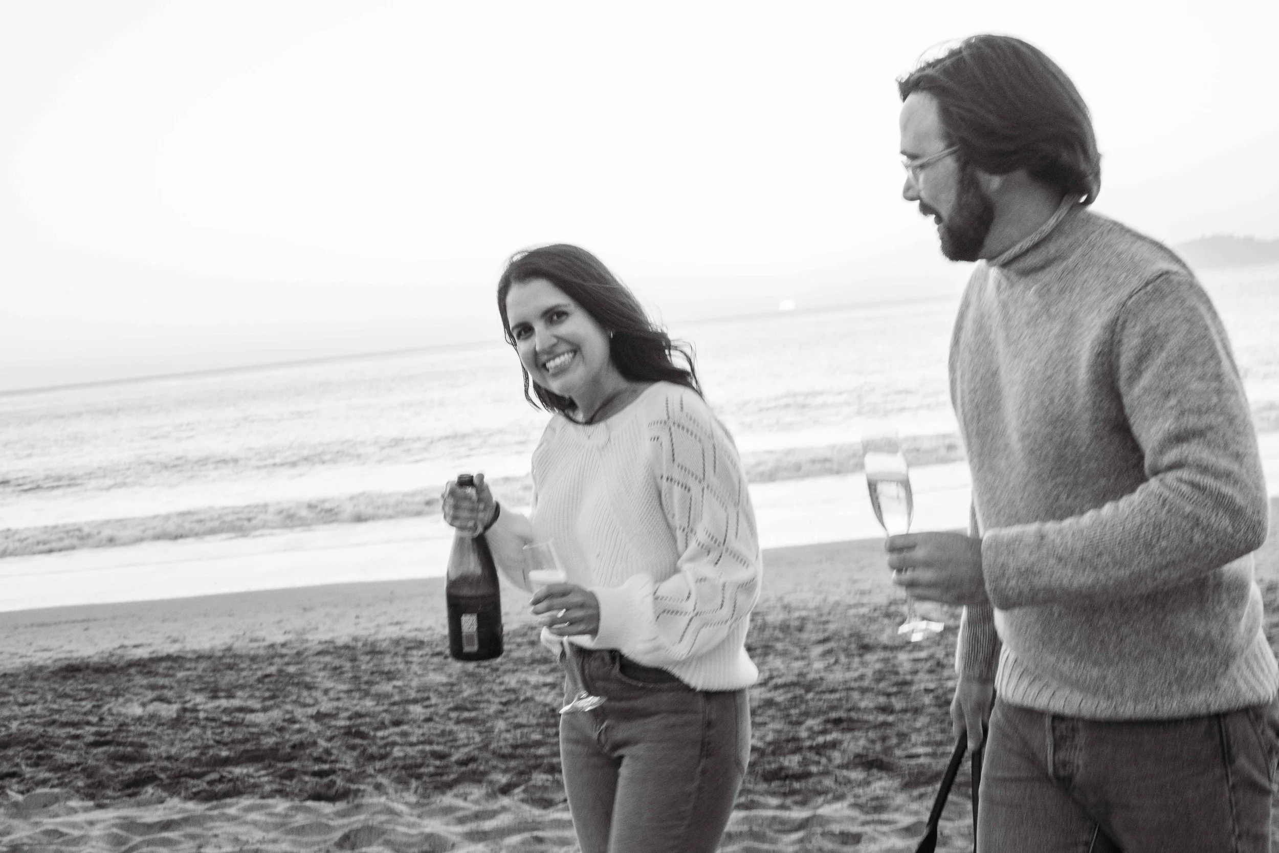 Black and white photo of a couple sharing a drink on the beach