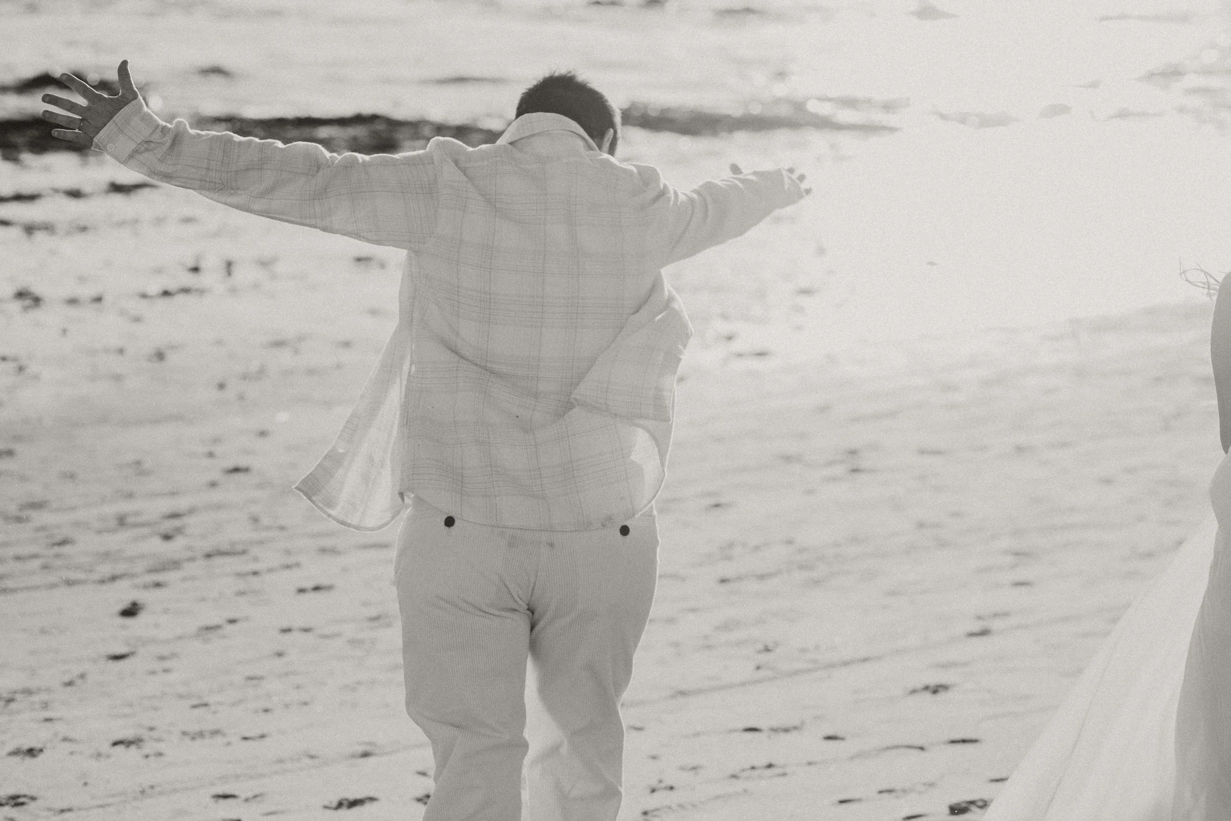 Black and white photo of a couple twirling on the beach