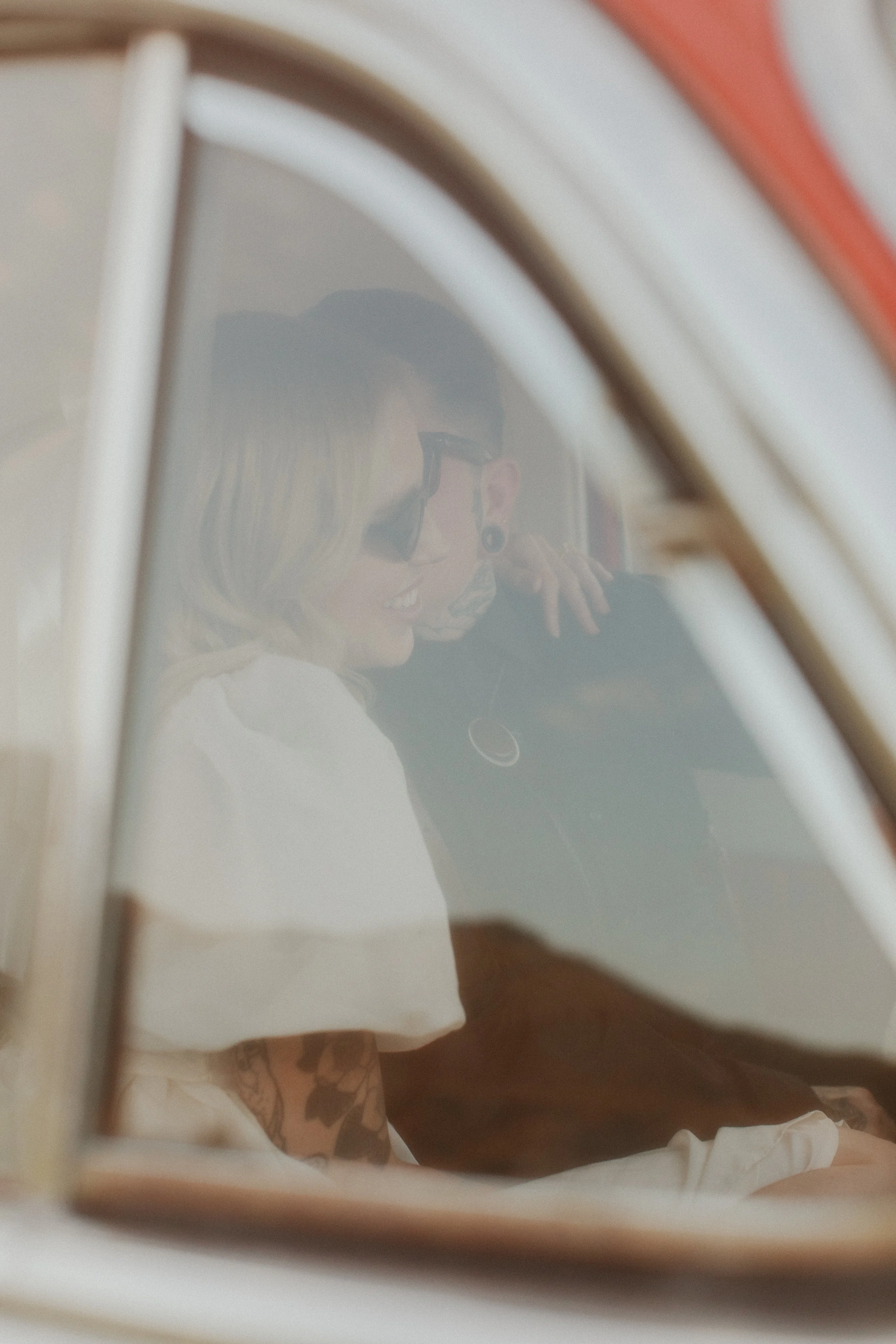 Bride reflected in the window of a vintage car