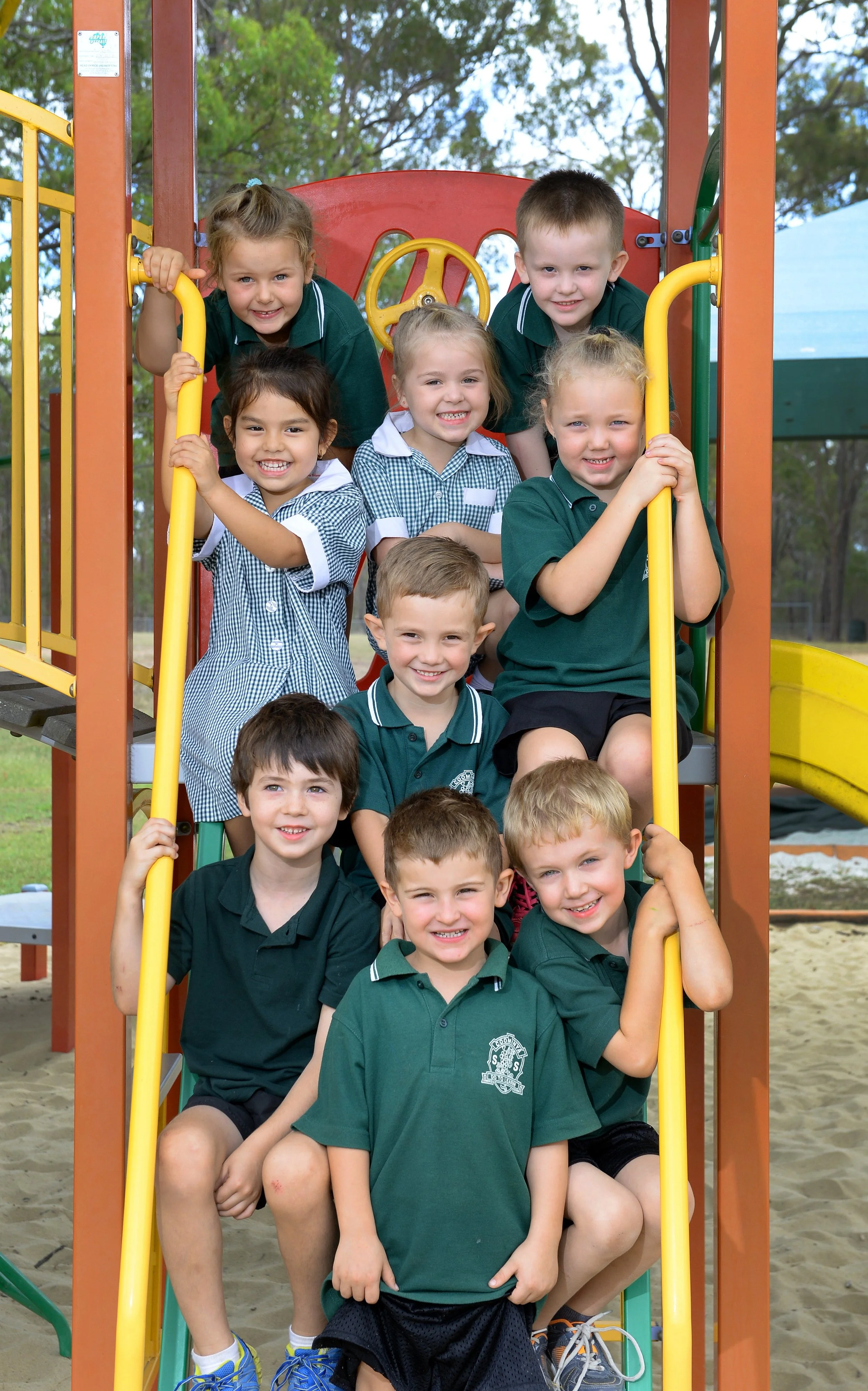 Group of school children smiling on playground stairs.